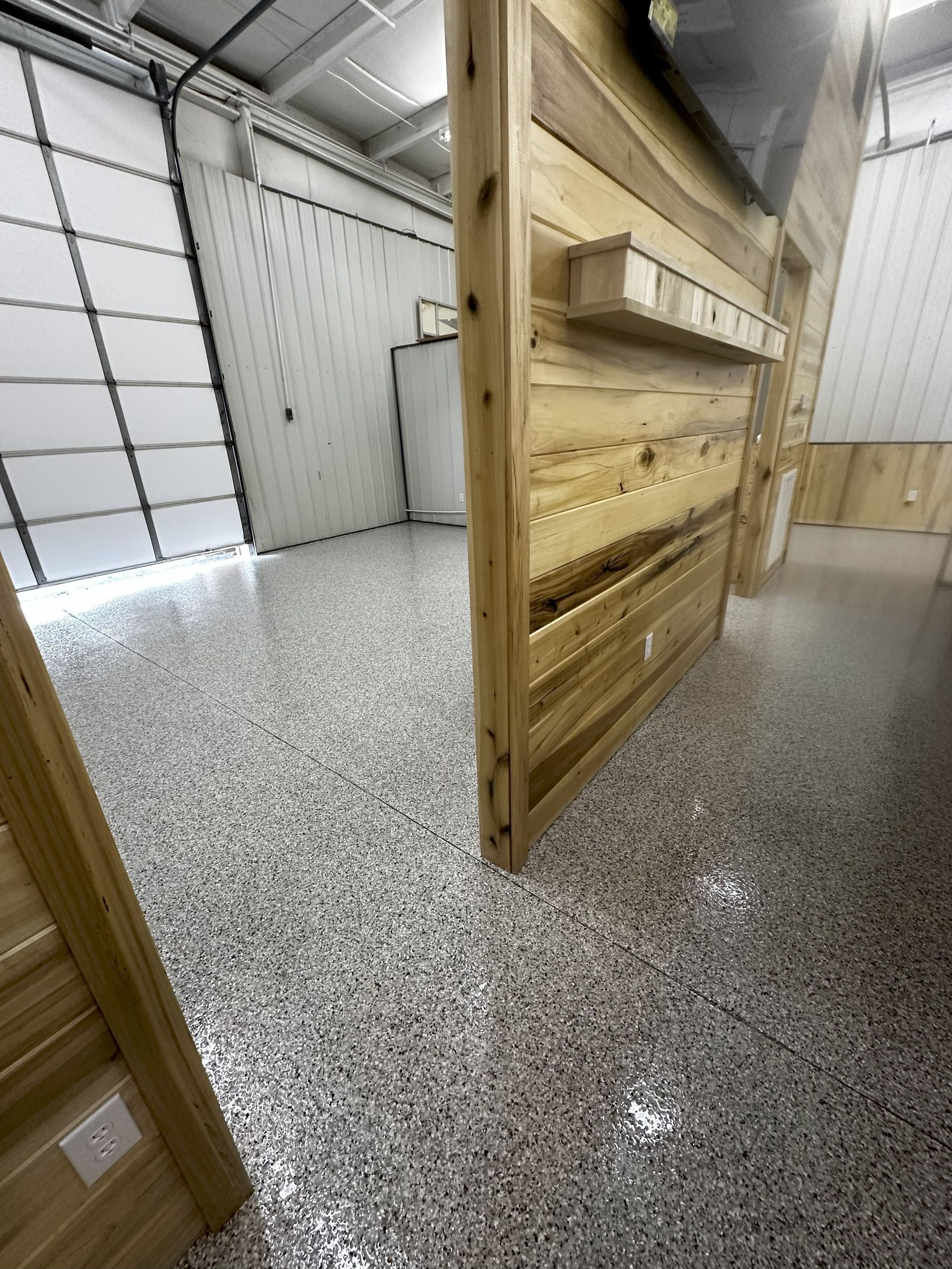 Spacious interior with a light-colored epoxy floor and wooden accents. Garage door is visible.