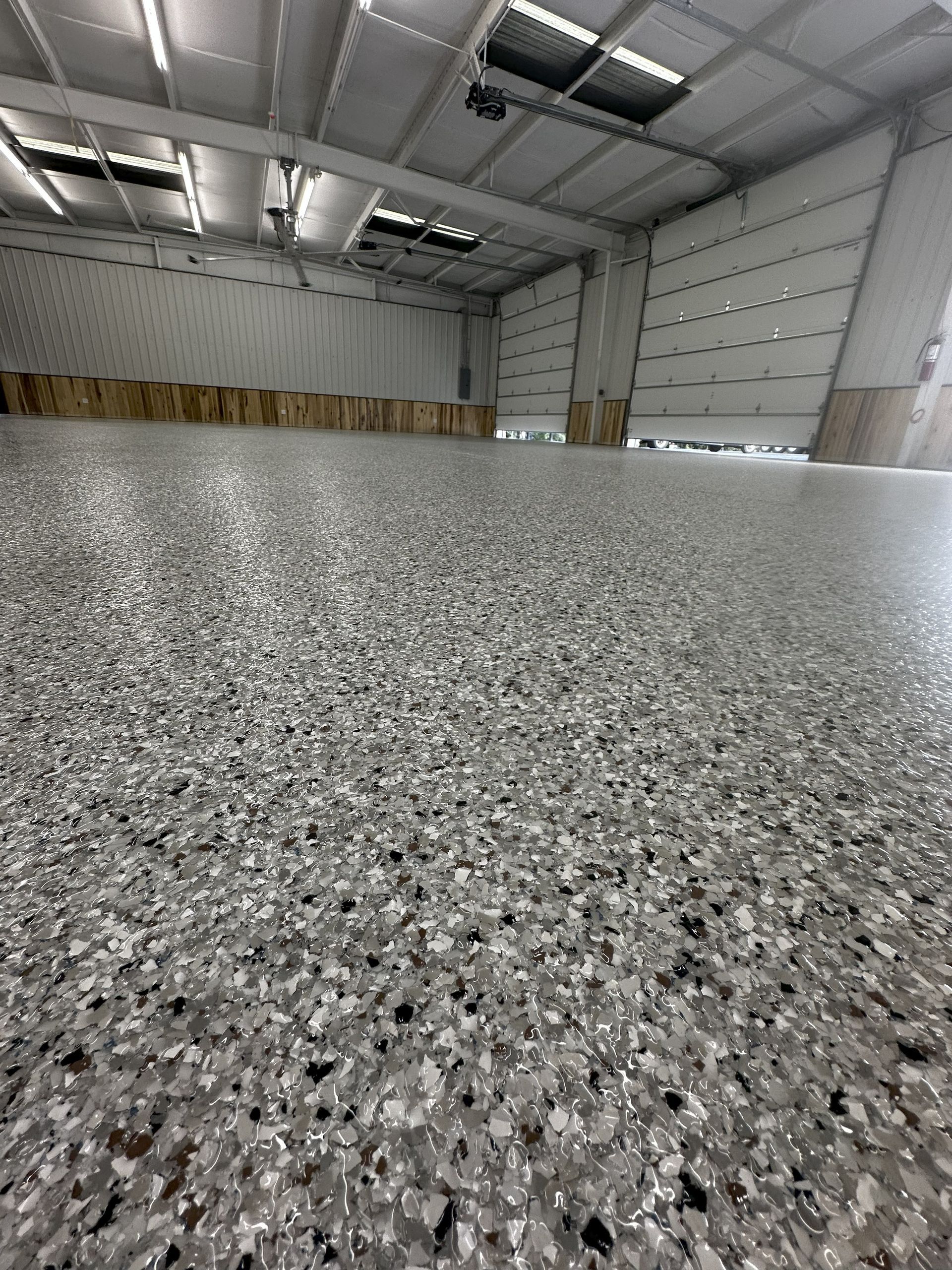 Gray speckled epoxy floor in a large, empty warehouse with a high ceiling.