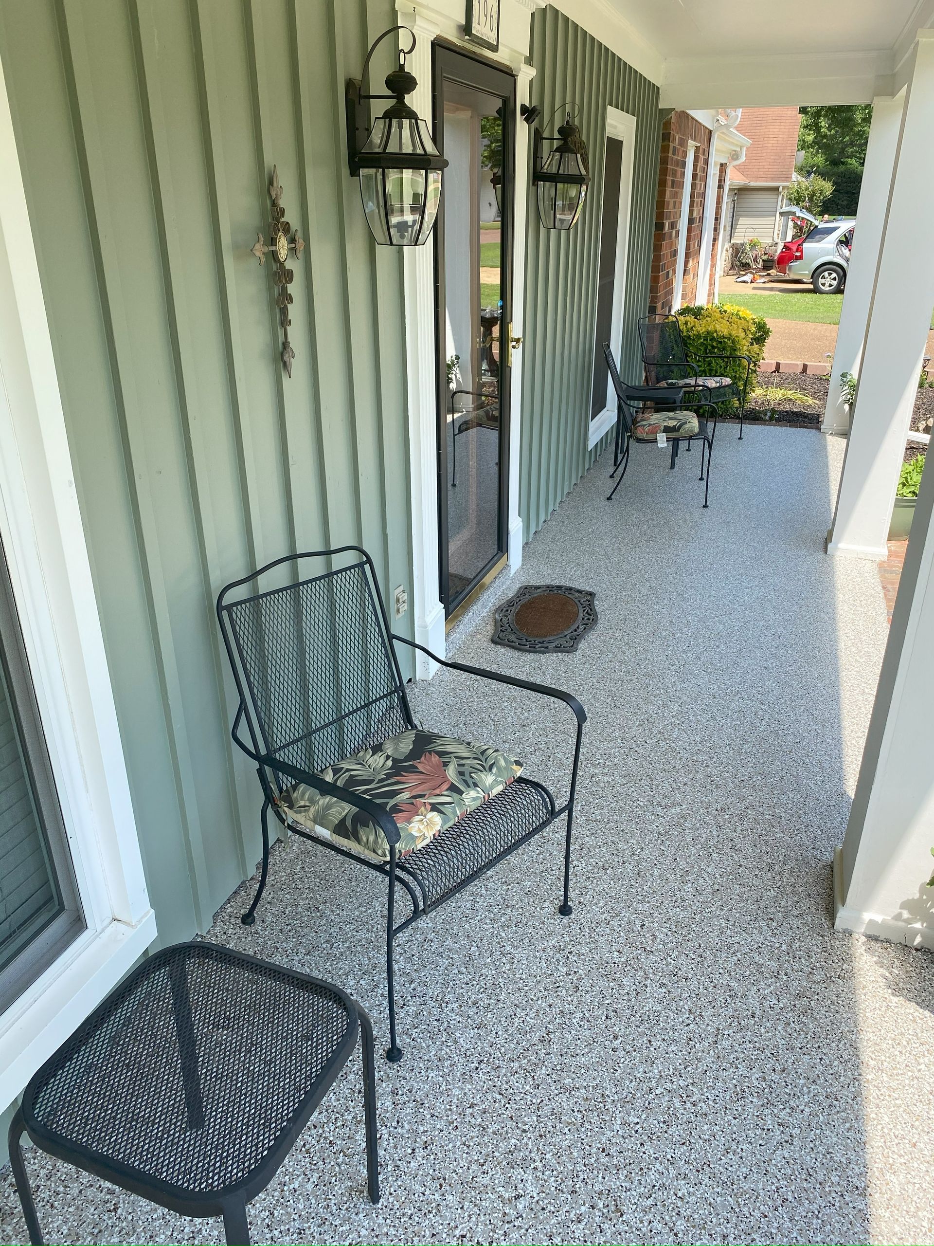 There is a chair and a table on the porch of a house.