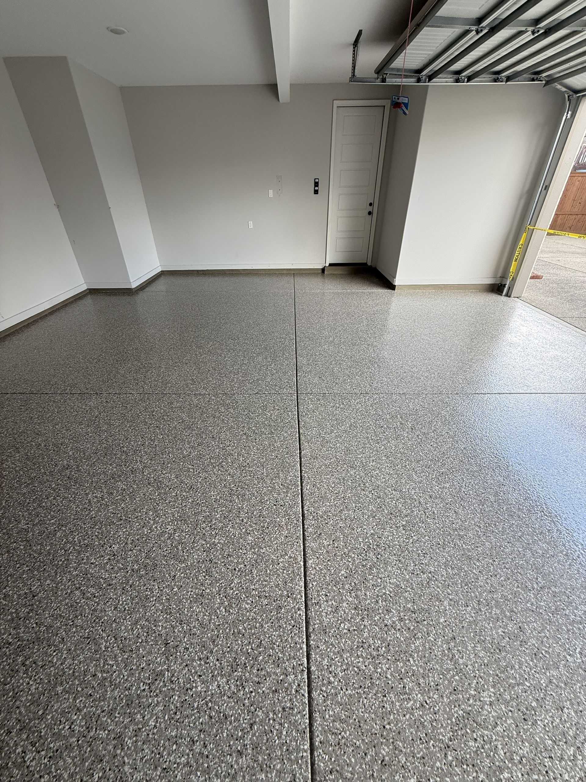 Garage floor with a speckled epoxy coating and a visible seam down the center.