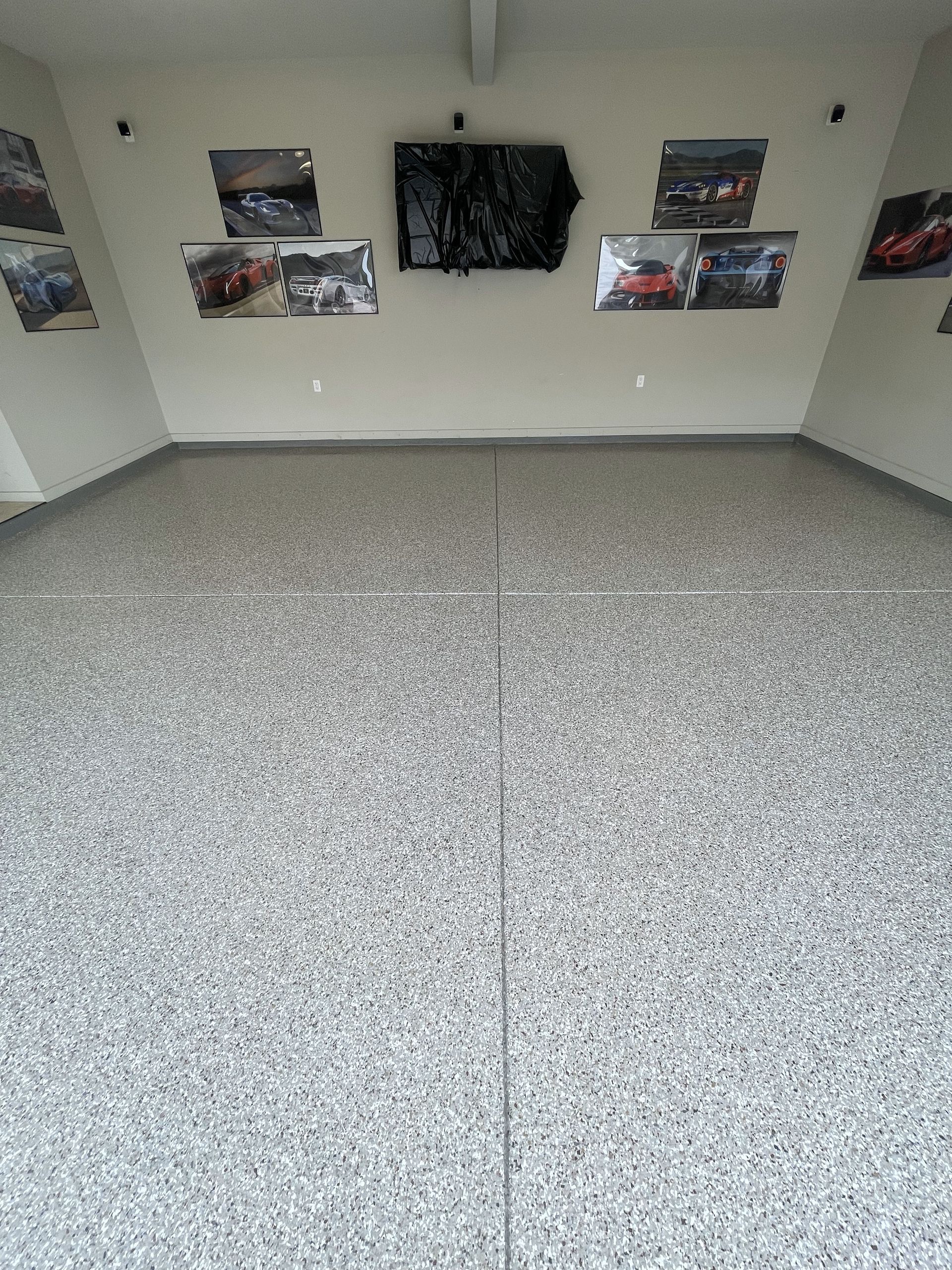 A garage with a gray floor and pictures of cars on the walls.