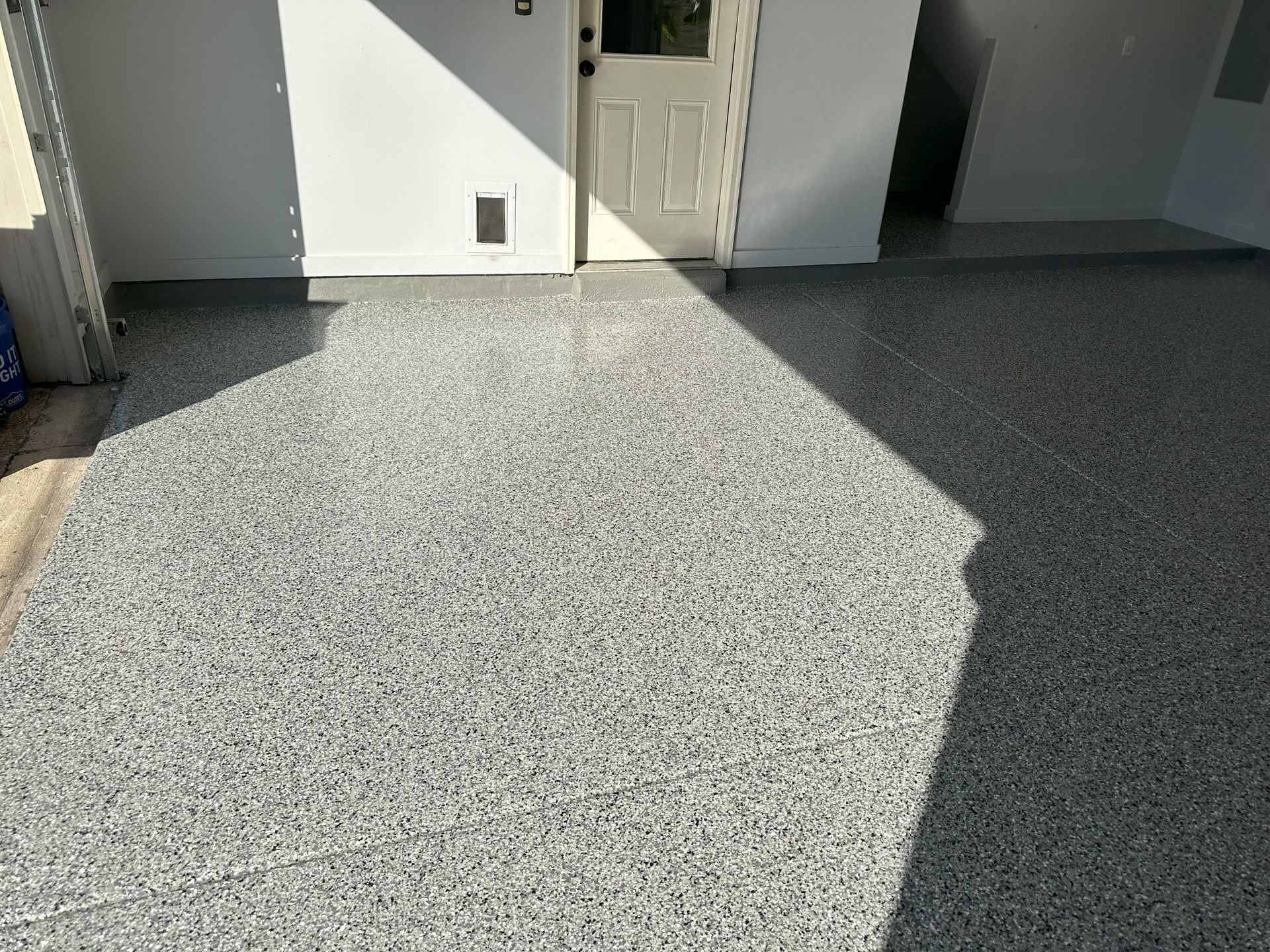 A garage with a gray concrete floor and a white door.