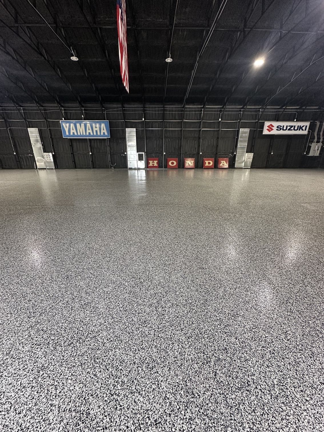 A large empty room with a yamaha and suzuki sign on the wall.