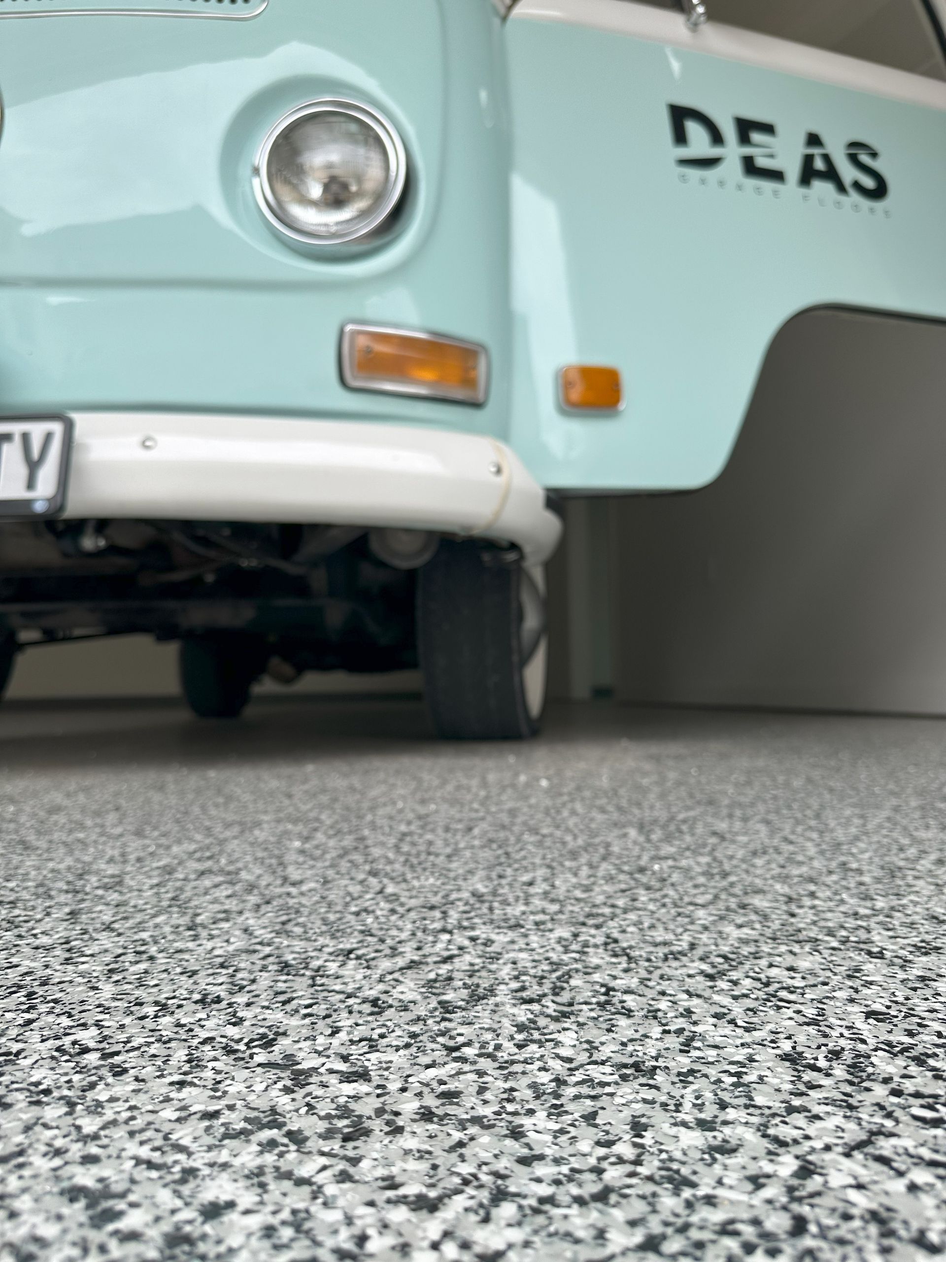 A blue van with deas written on the side is parked in a garage