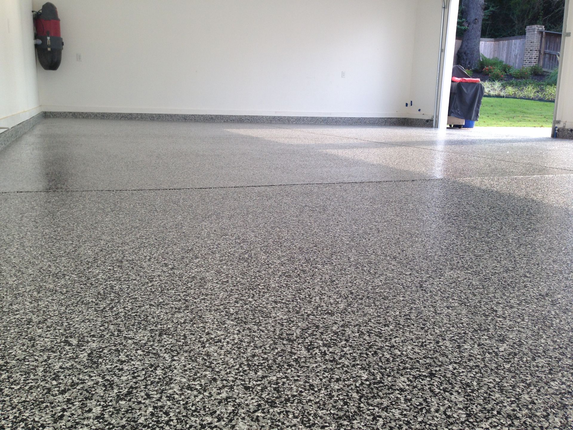 A garage with a concrete floor and a tire rack on the wall.