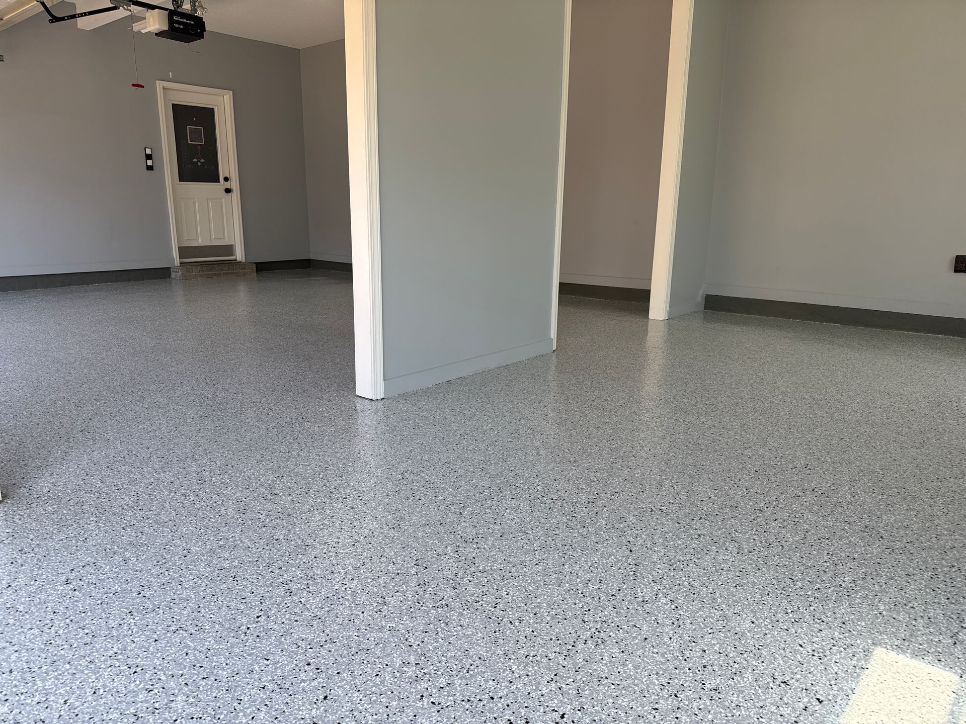 An empty room with a gray floor and a door.