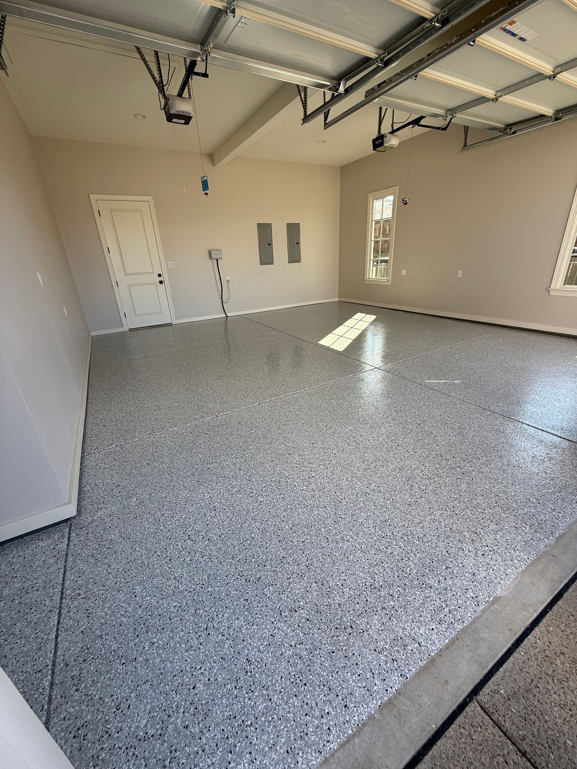 Empty garage with speckled gray floor and neutral walls.