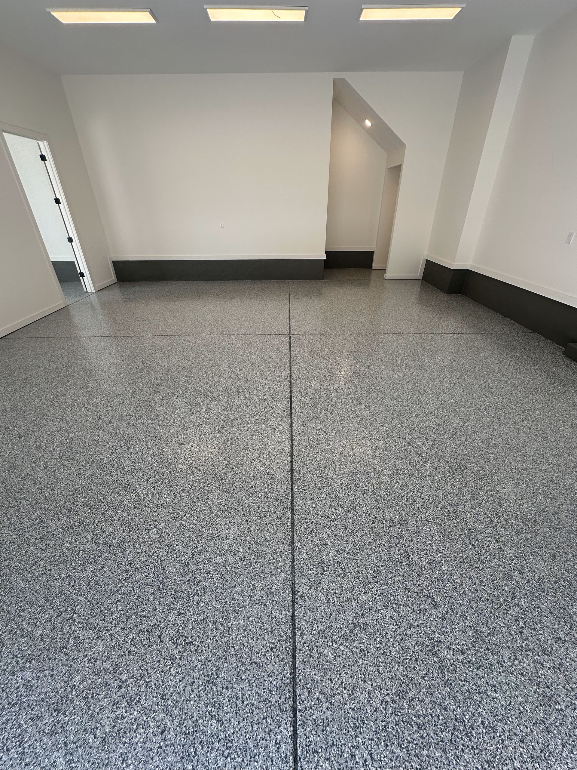 A large empty room with a gray floor and white walls.