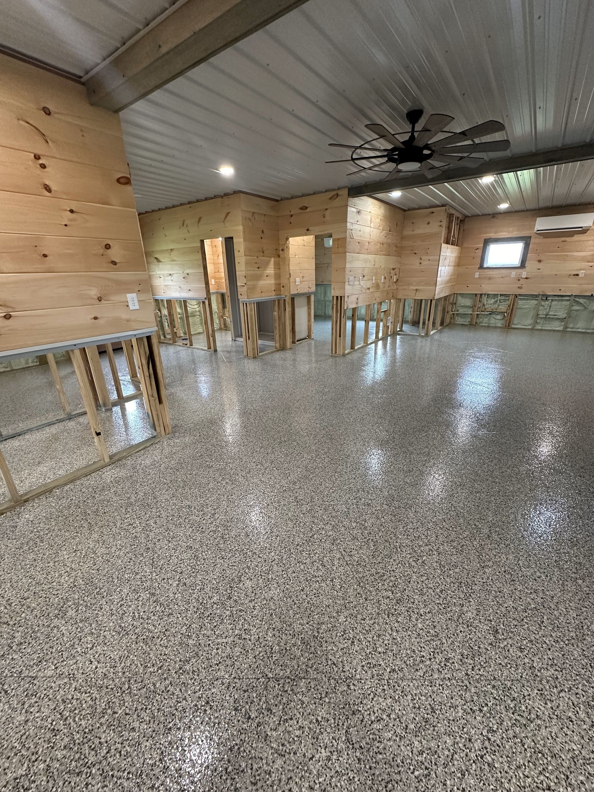 A large room with a ceiling fan and a concrete floor.