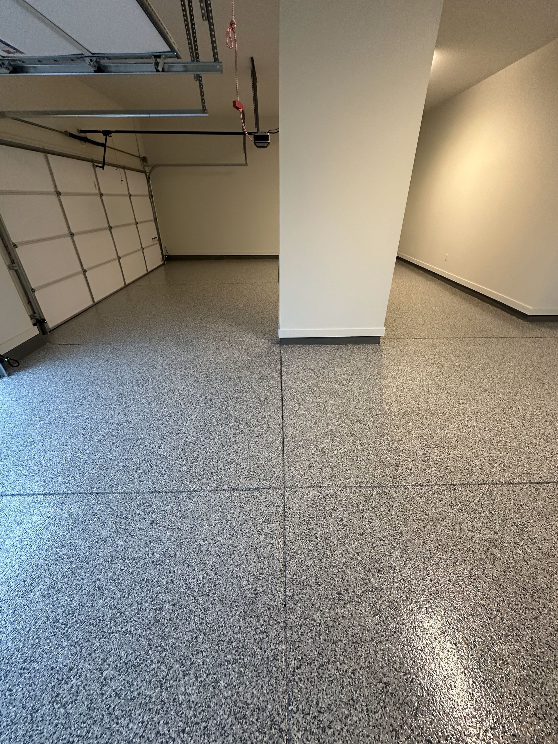 A garage with a garage door open and a gray floor.