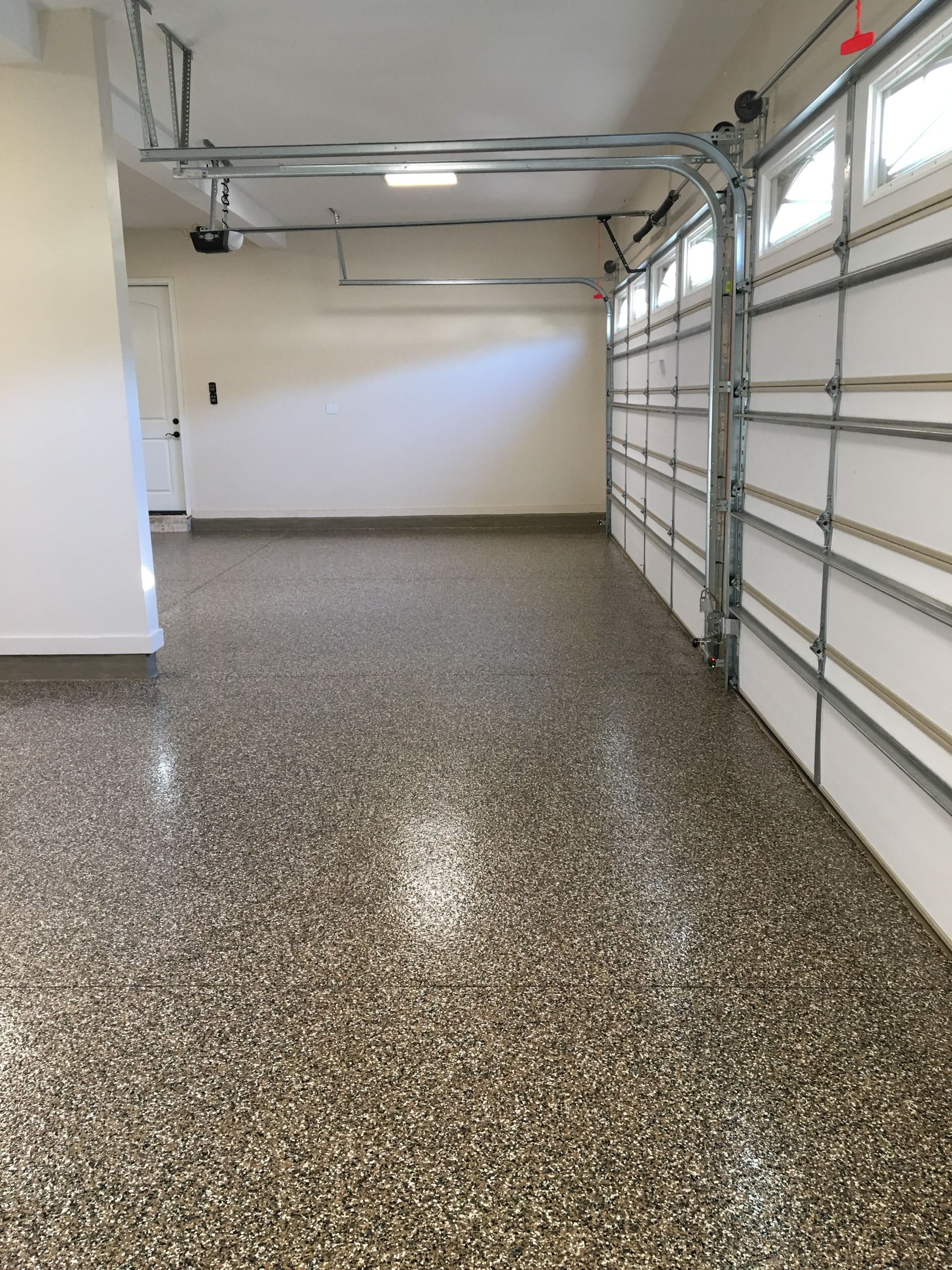 An empty garage with a garage door open and a shiny floor.