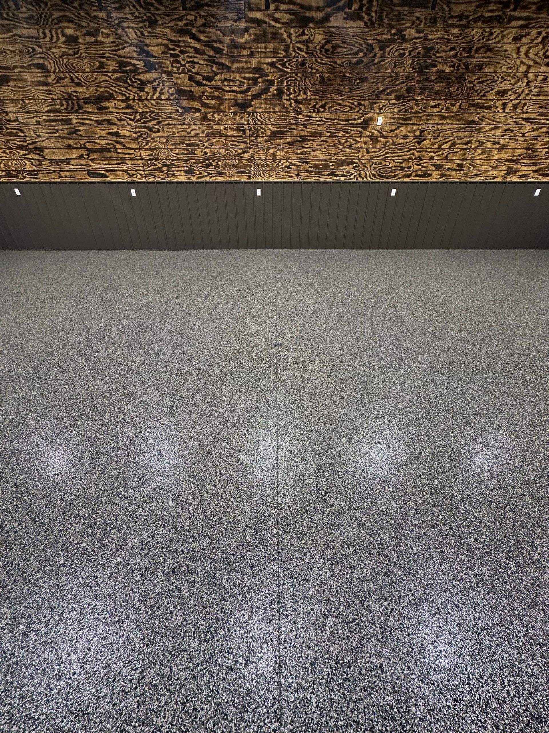 Dark, textured ceiling above a dark, textured wall. Eight small lights are above the wall.