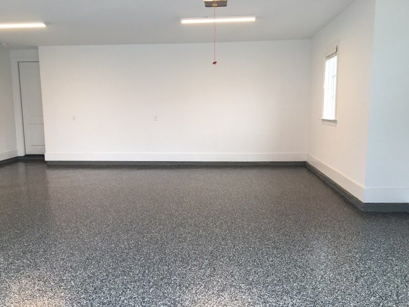 An empty garage with a gray floor and white walls