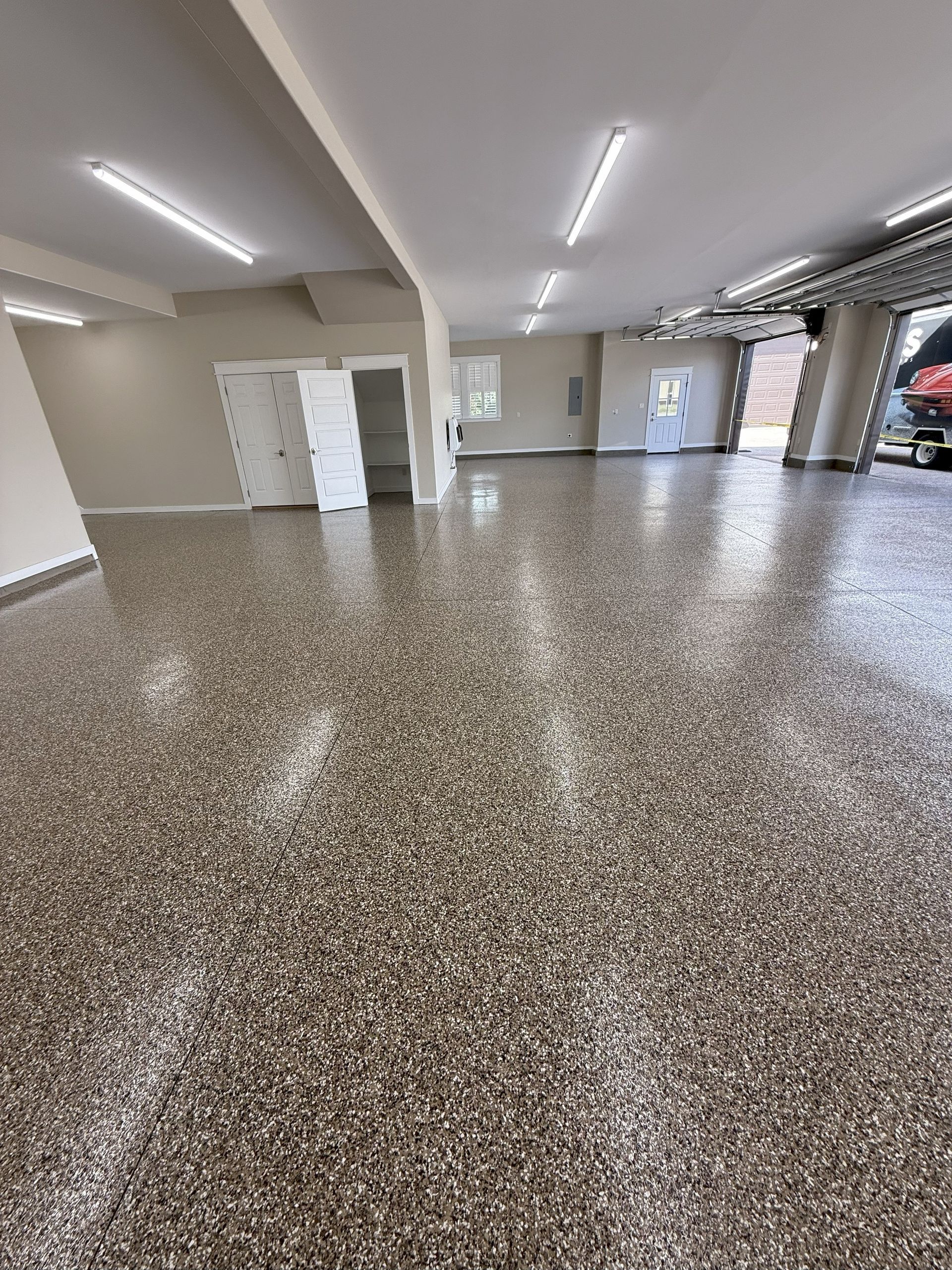 Spacious garage with a speckled floor and bright overhead lights.