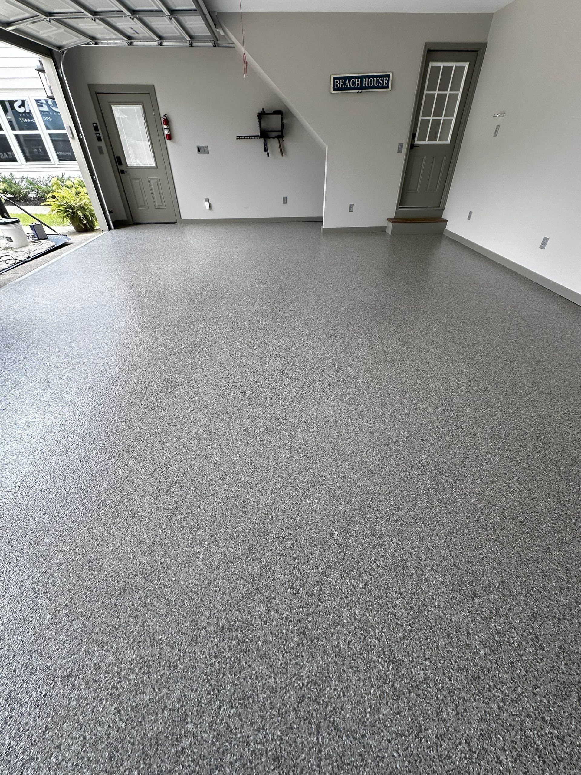 Garage with a speckled gray epoxy floor, two doors, and a partially open garage door.