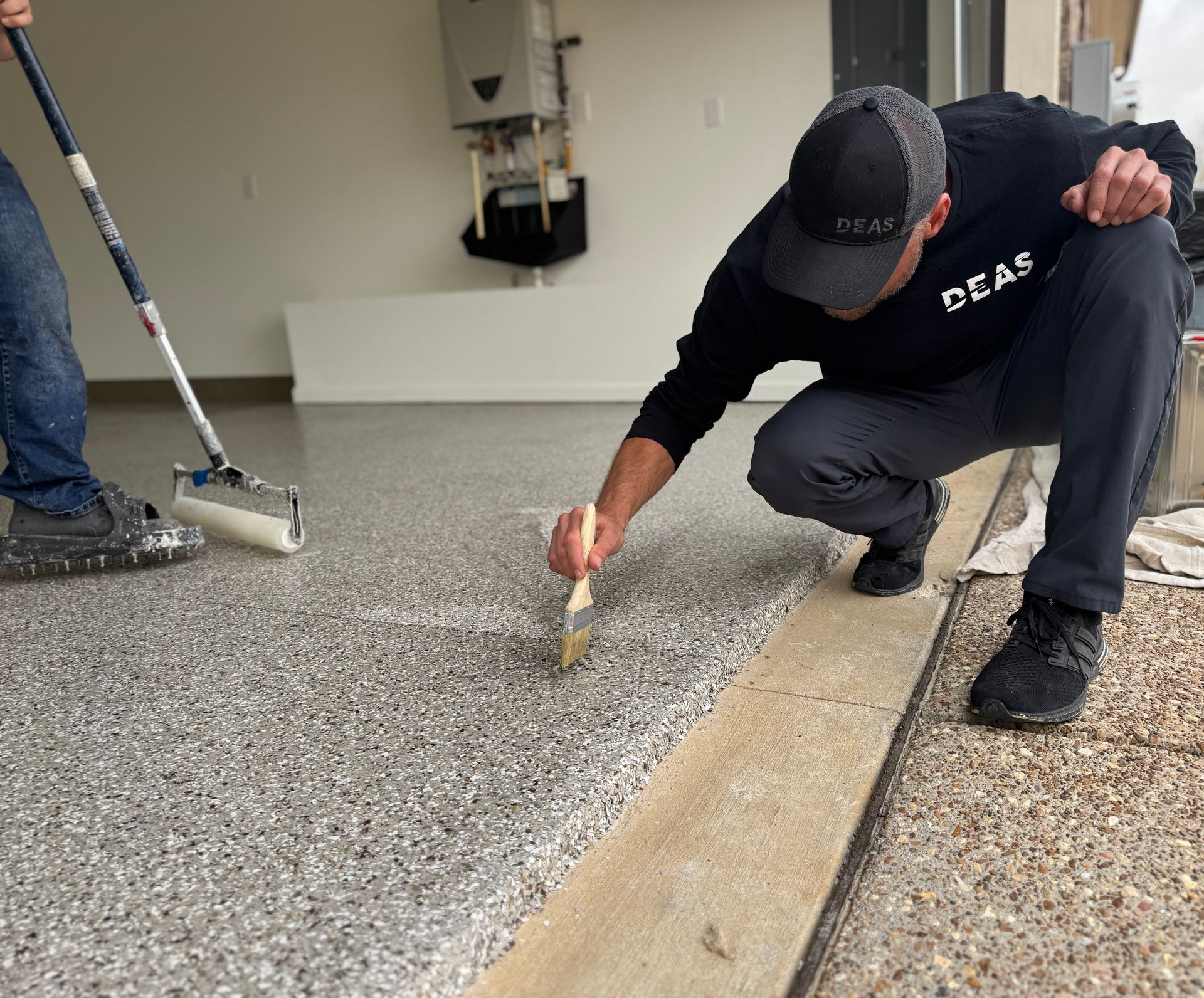 Worker kneeling on a floor applying material along a concrete seam with a trowel