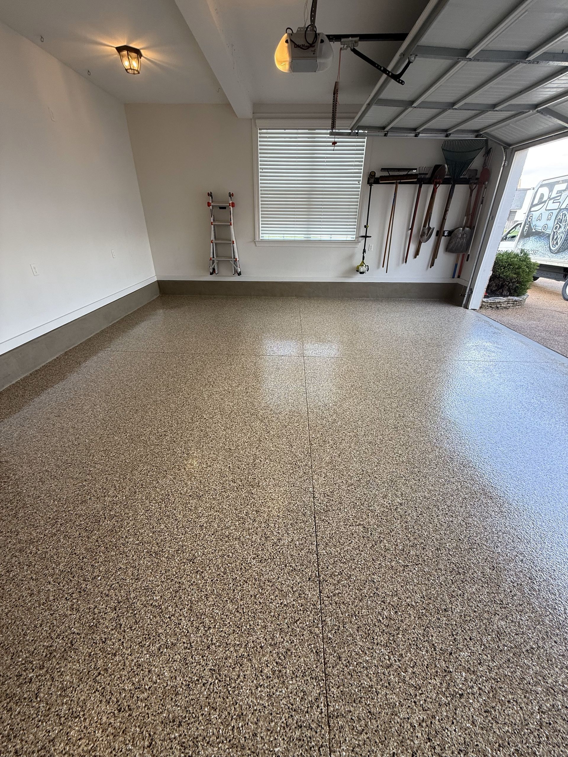 A garage with a ladder and a garage door open.