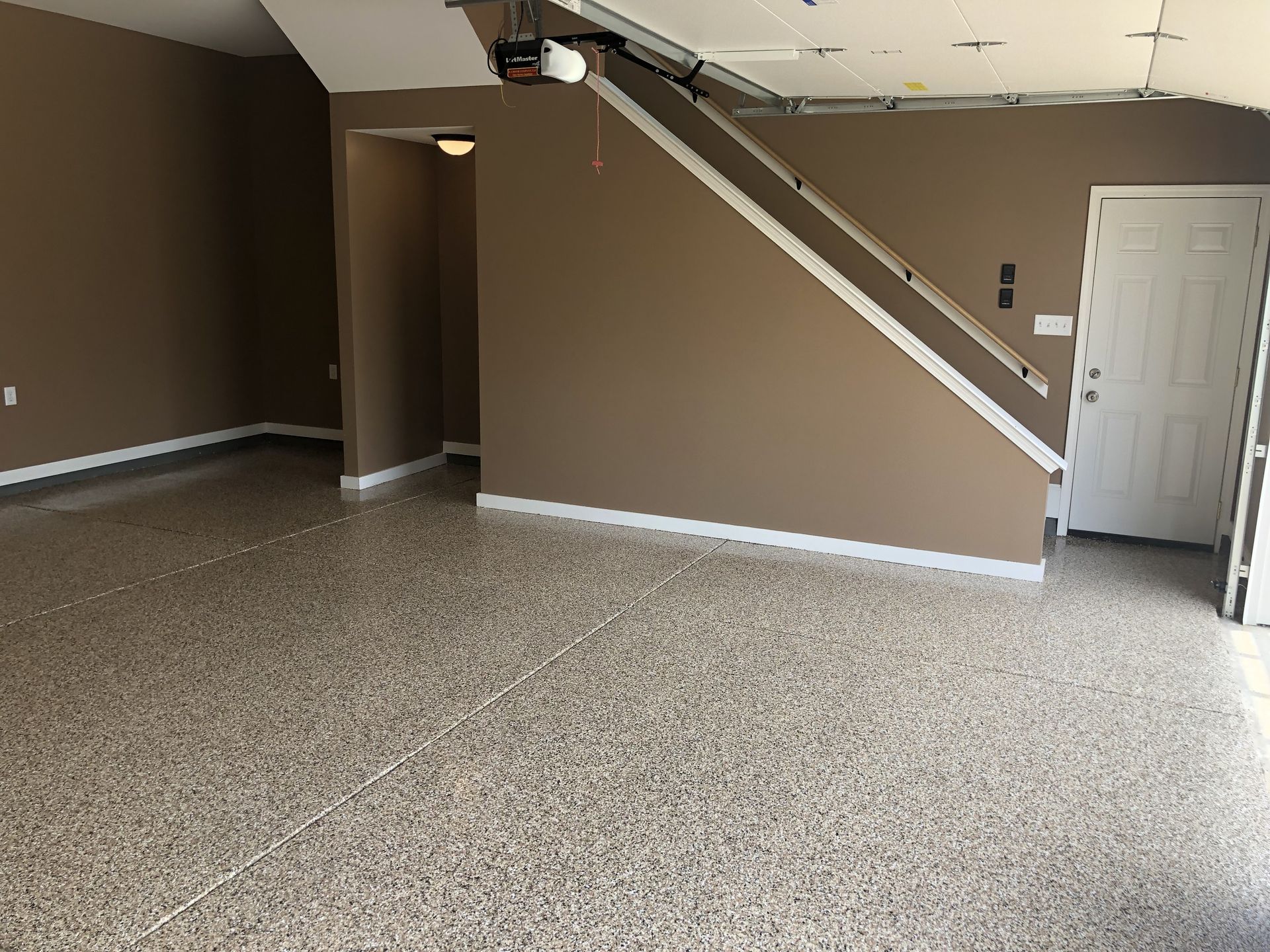An empty garage with stairs and a ceiling fan