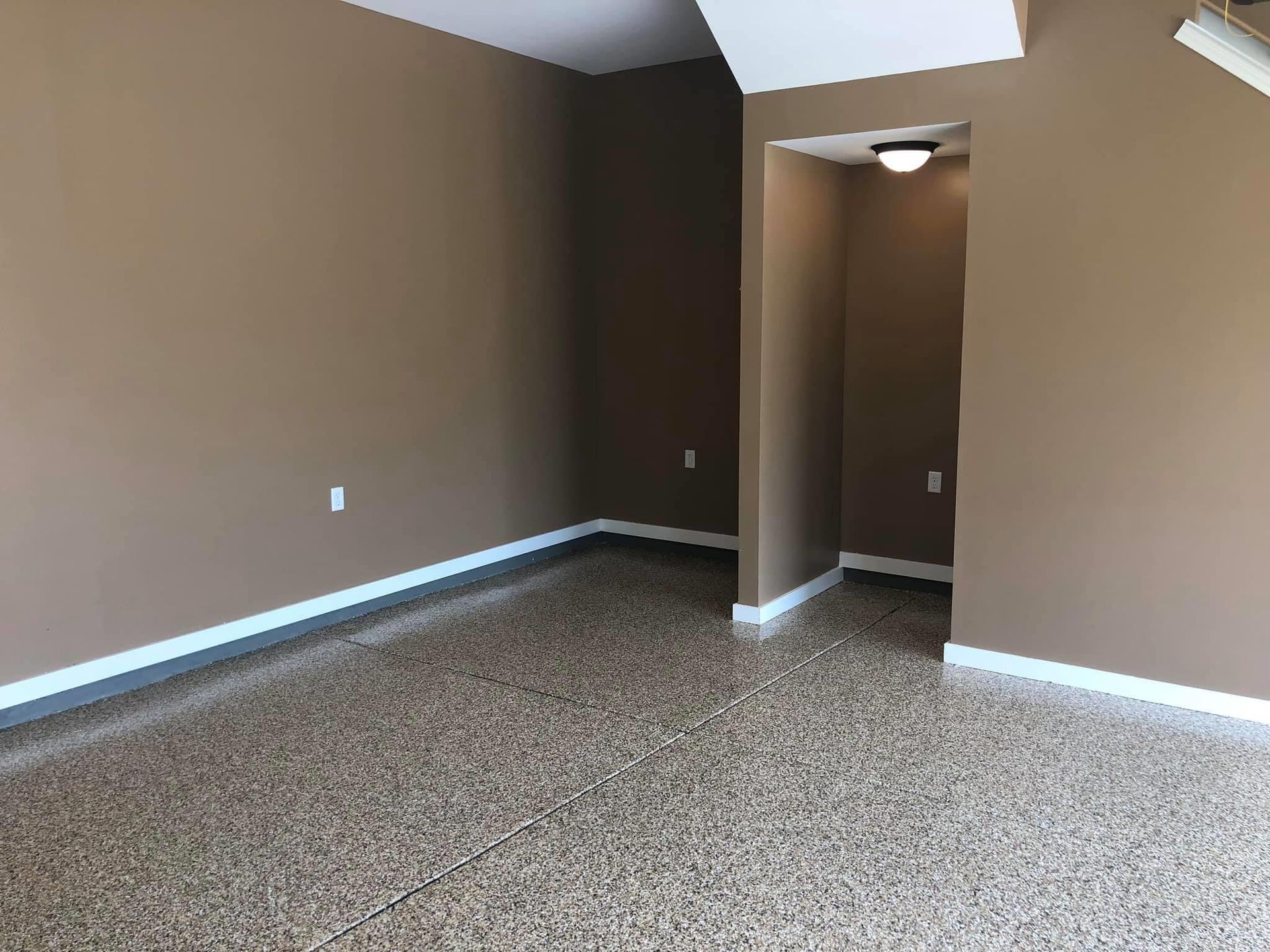 An empty living room with brown walls and a ceiling fan.