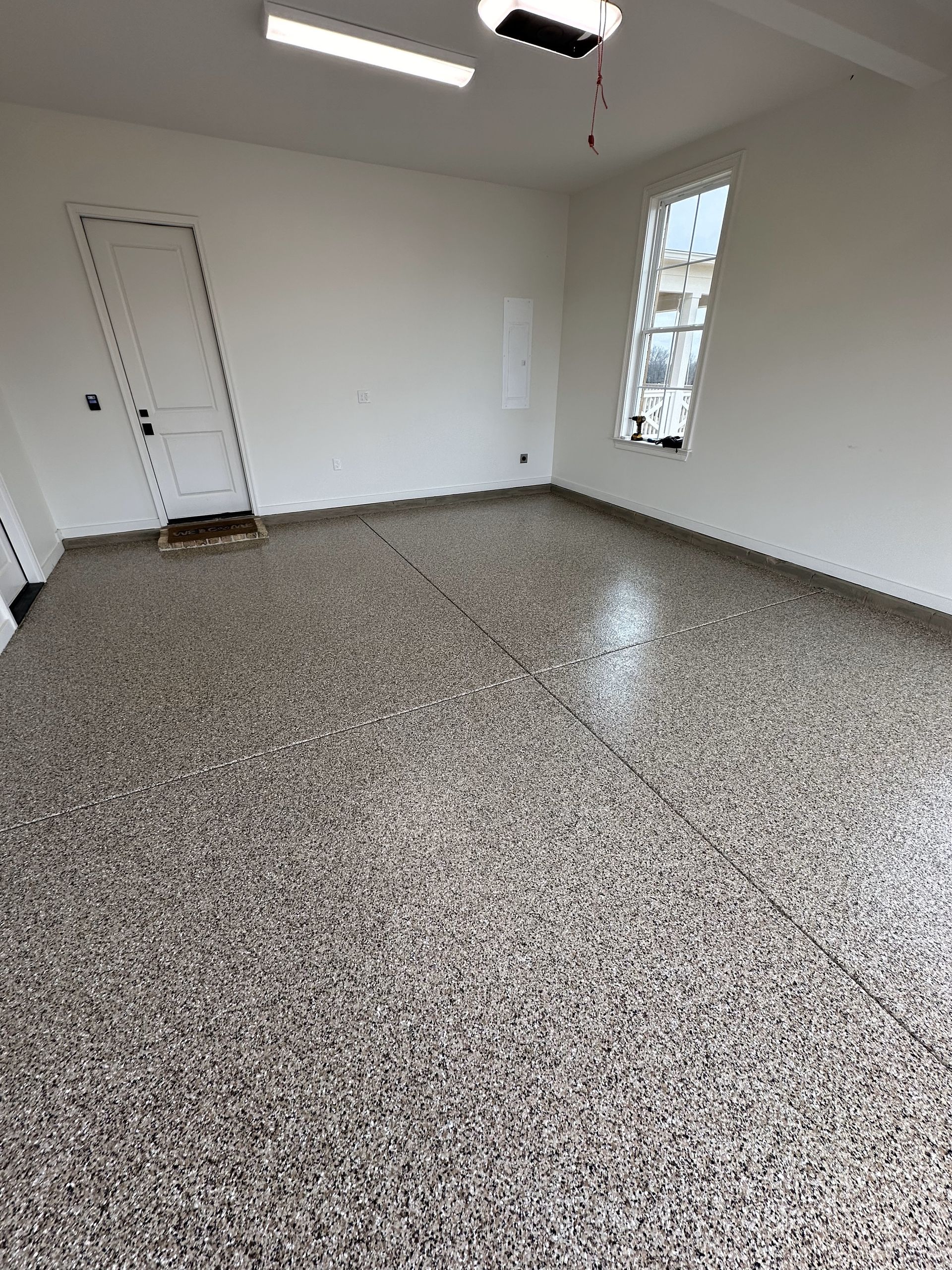 A large empty room with a concrete floor and white walls.