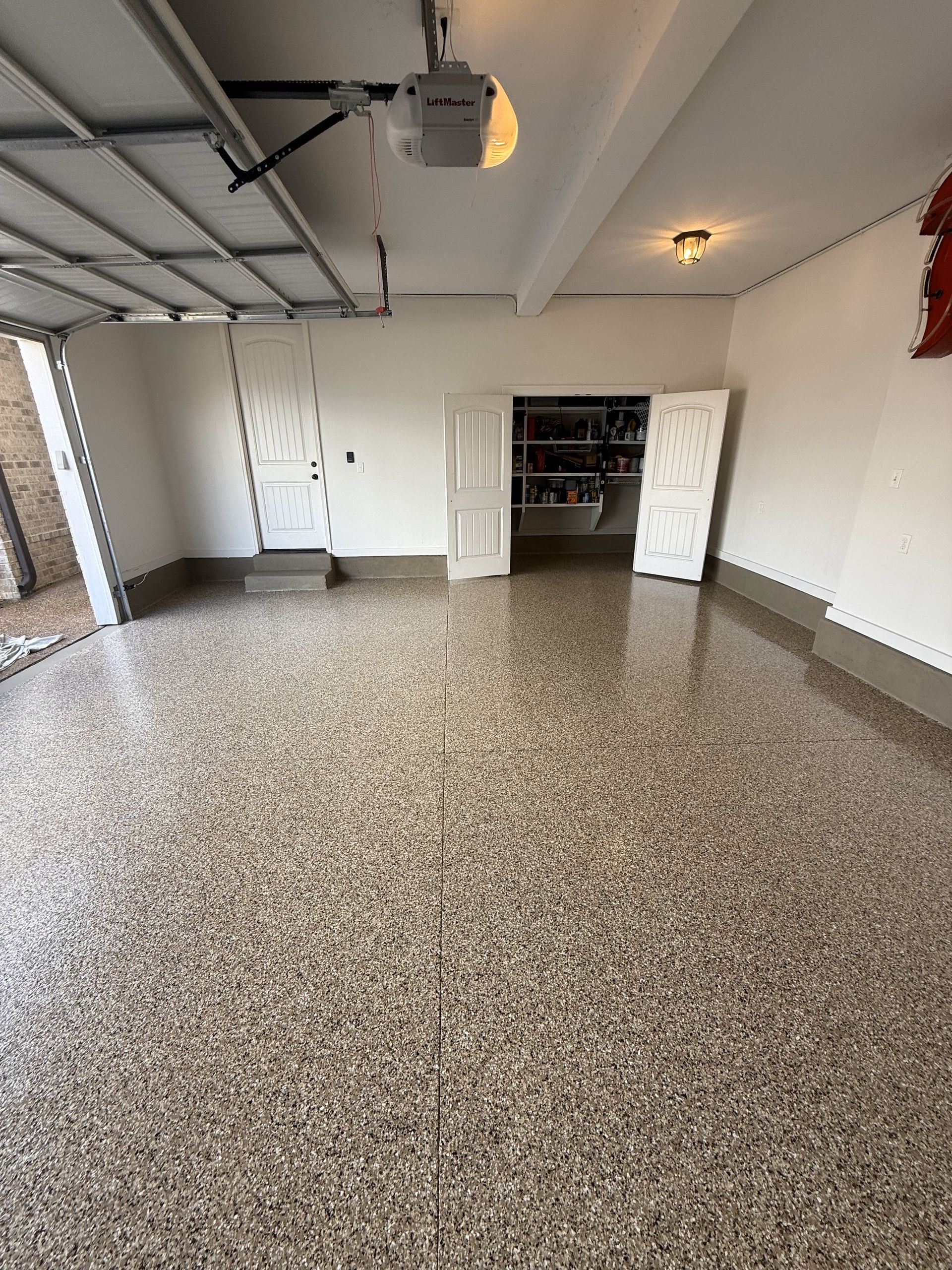 A garage with a concrete floor and a garage door open.