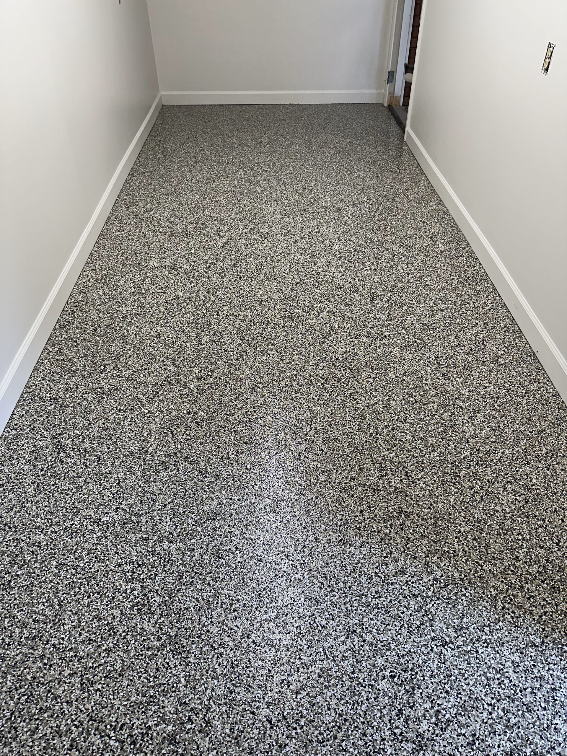 A hallway with a gray carpeted floor and white walls.