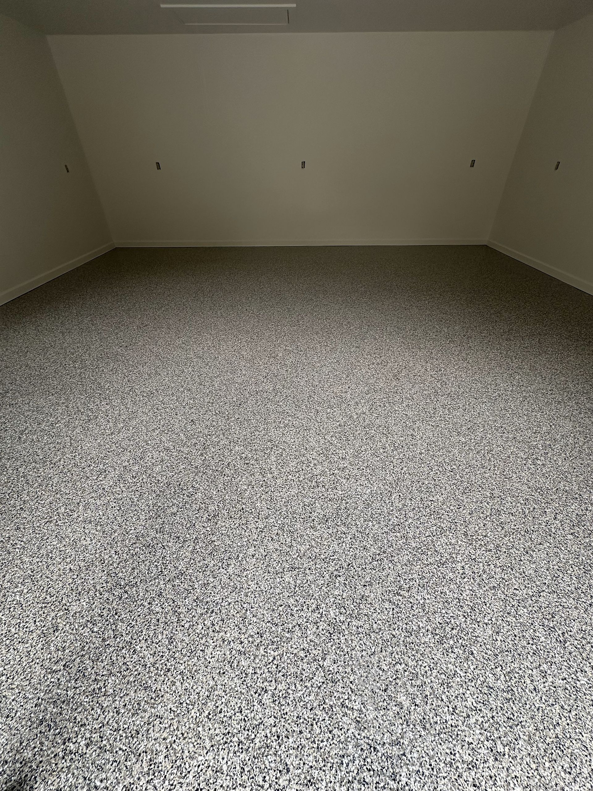 An empty room with a gray carpeted floor and white walls.