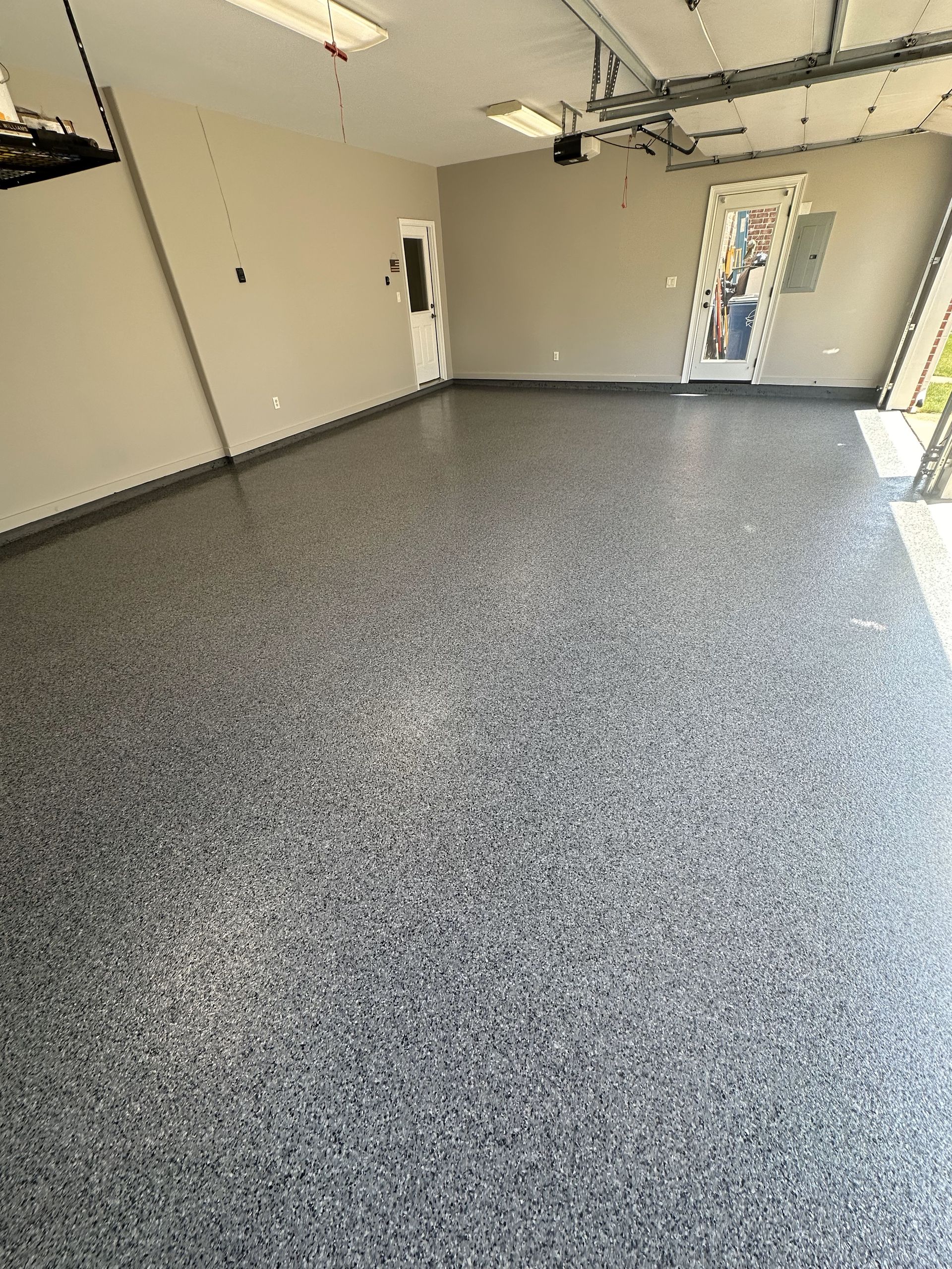 A garage with a gray floor and a garage door.