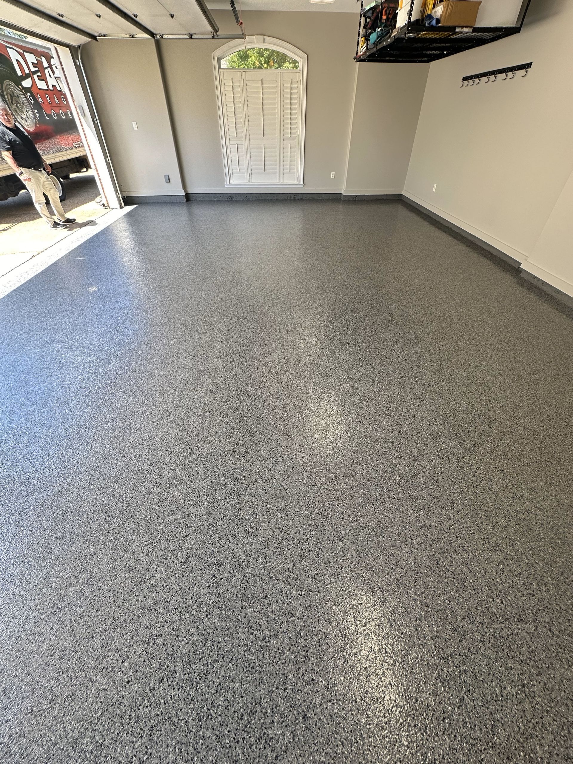 A man is standing in a garage with a gray floor.