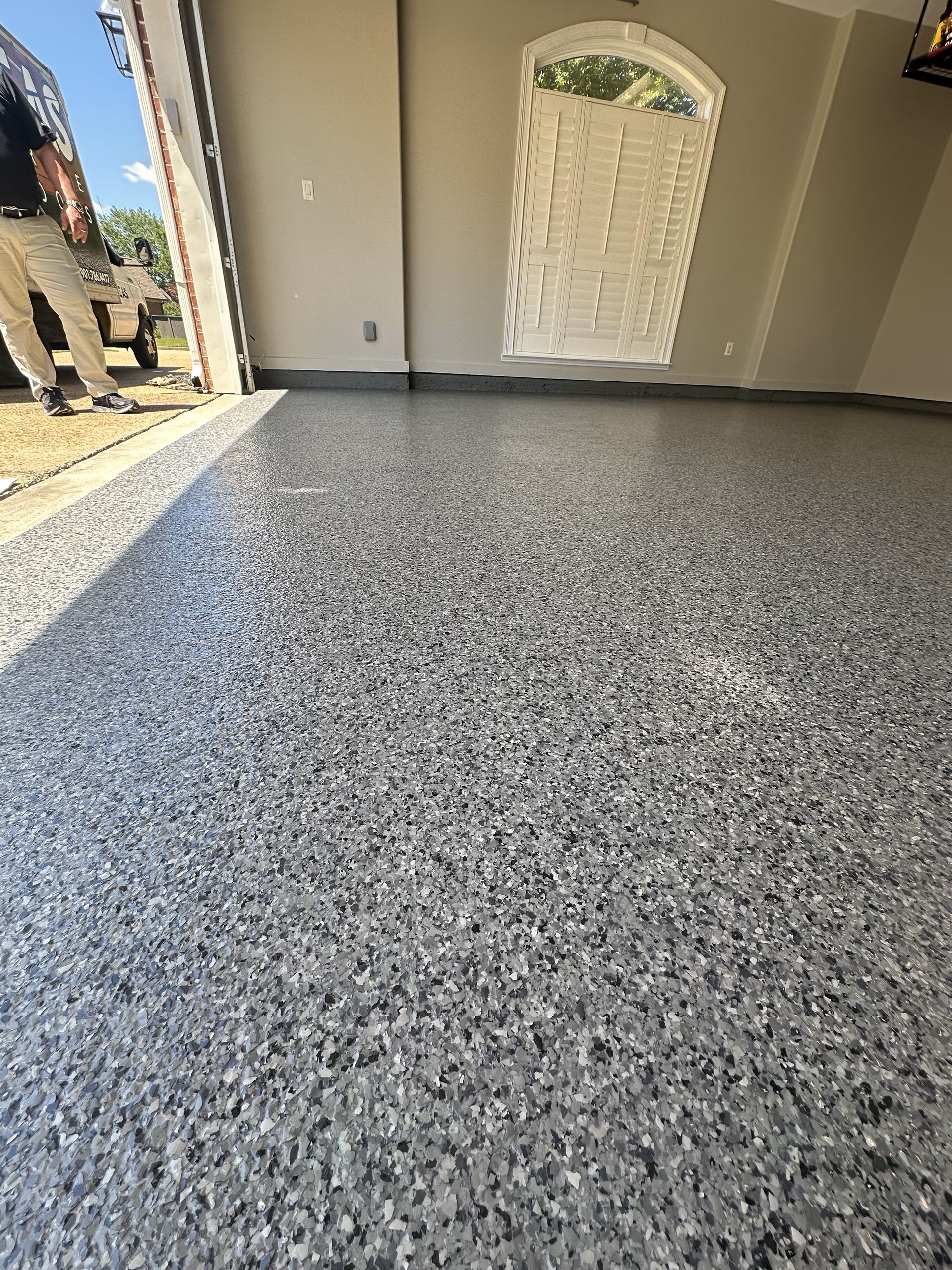 A man is standing in a garage with a gray floor.
