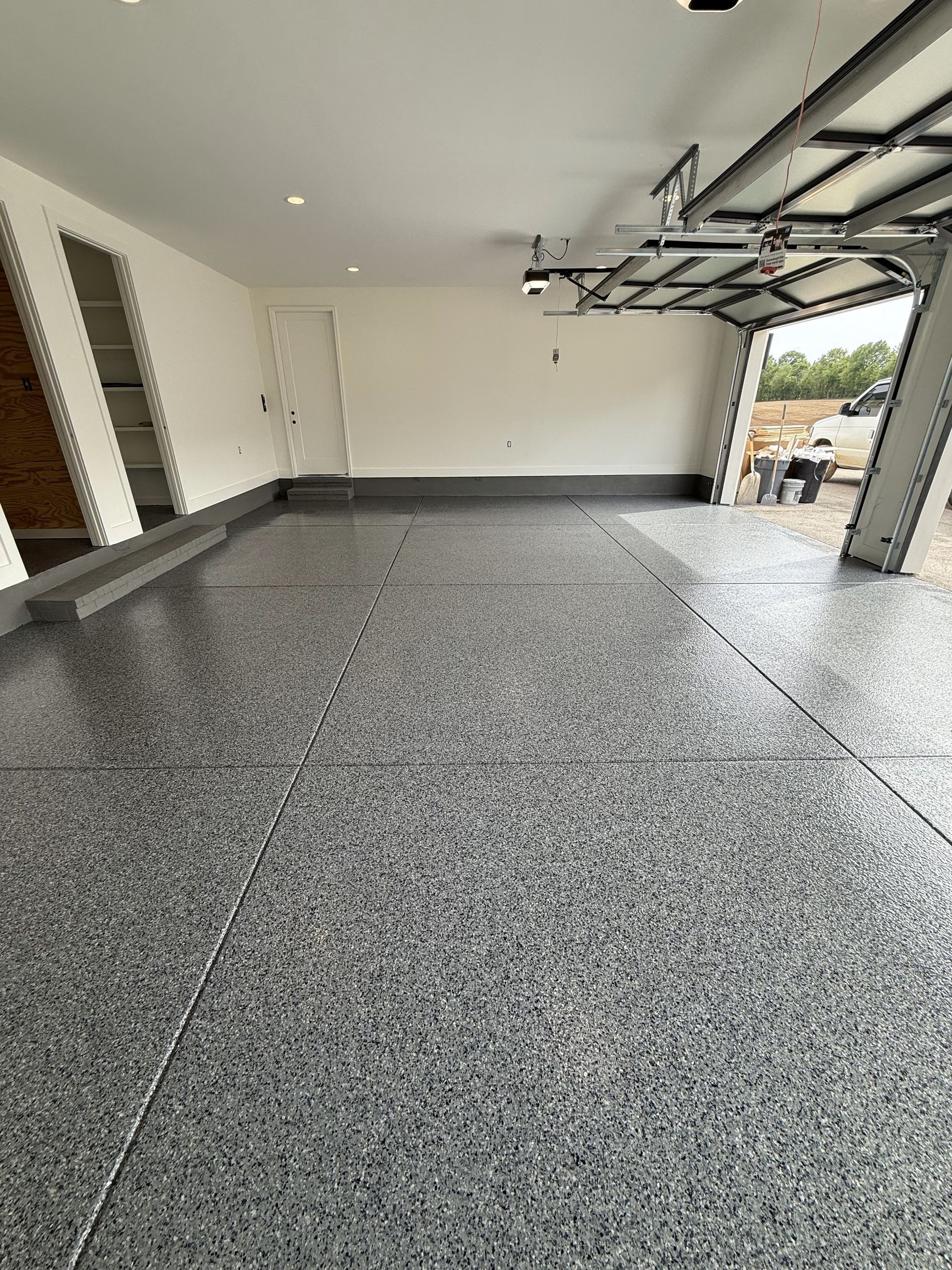 A garage with a gray floor and a white wall.