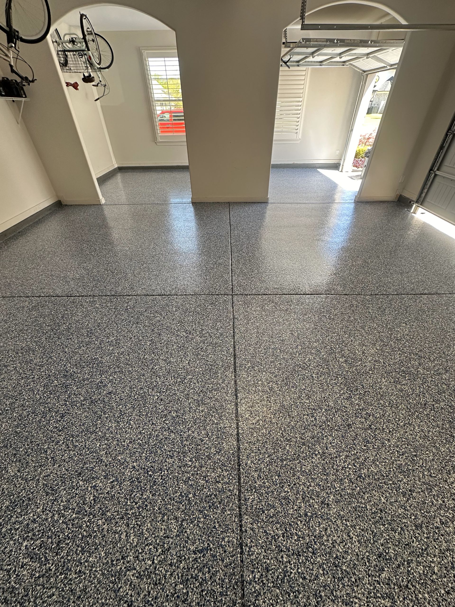 A garage with a gray floor and a bicycle on the wall.