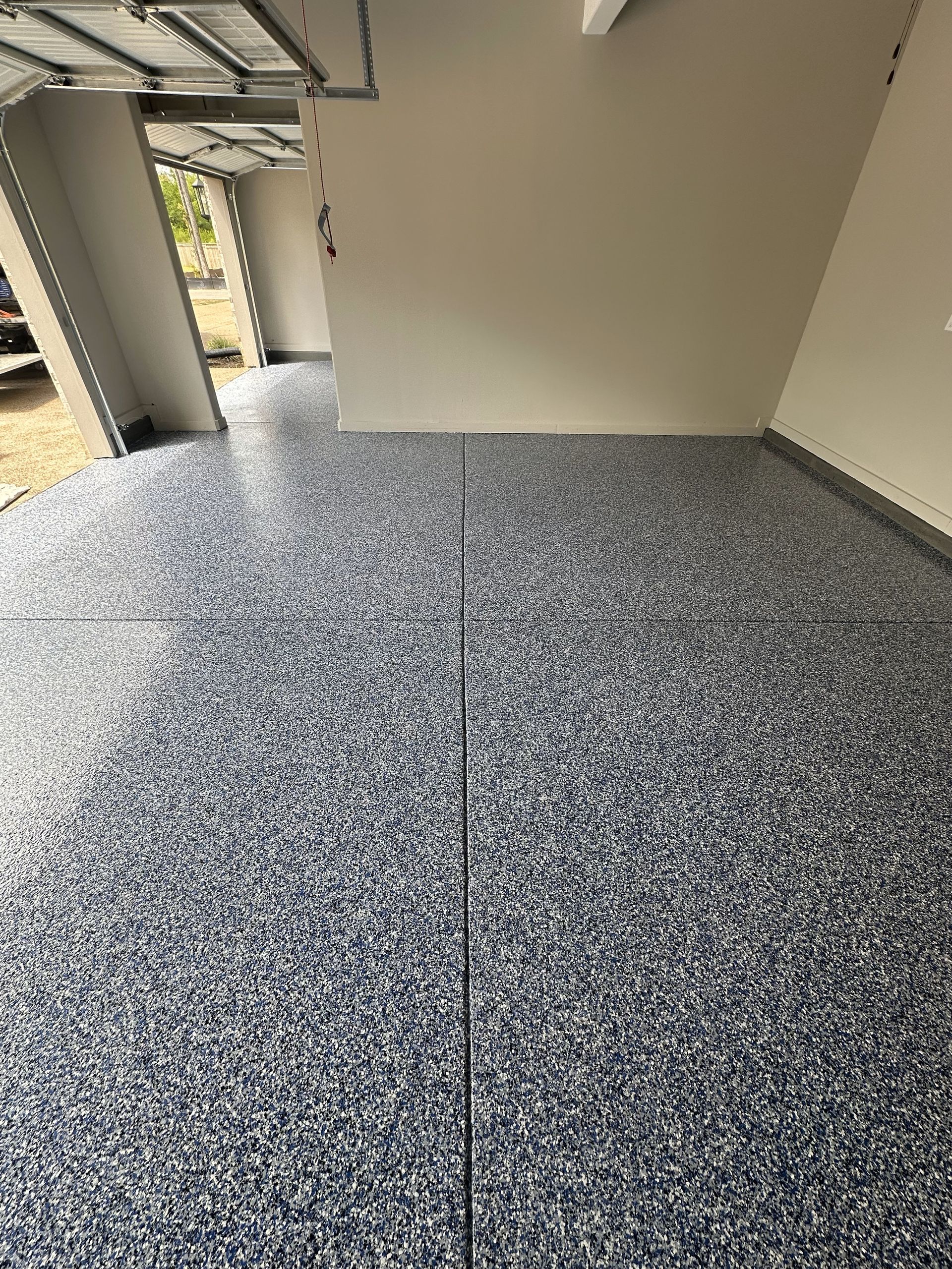 A garage with a gray floor and a white wall.