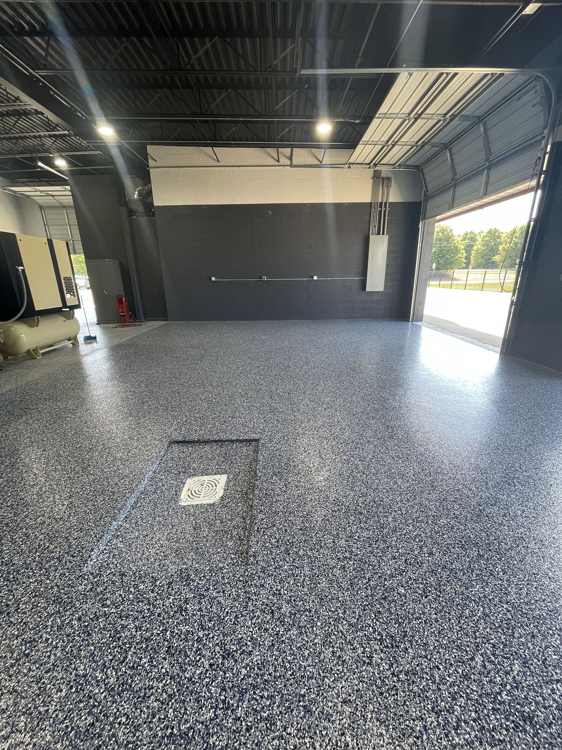 A garage with a gray floor and a black wall.