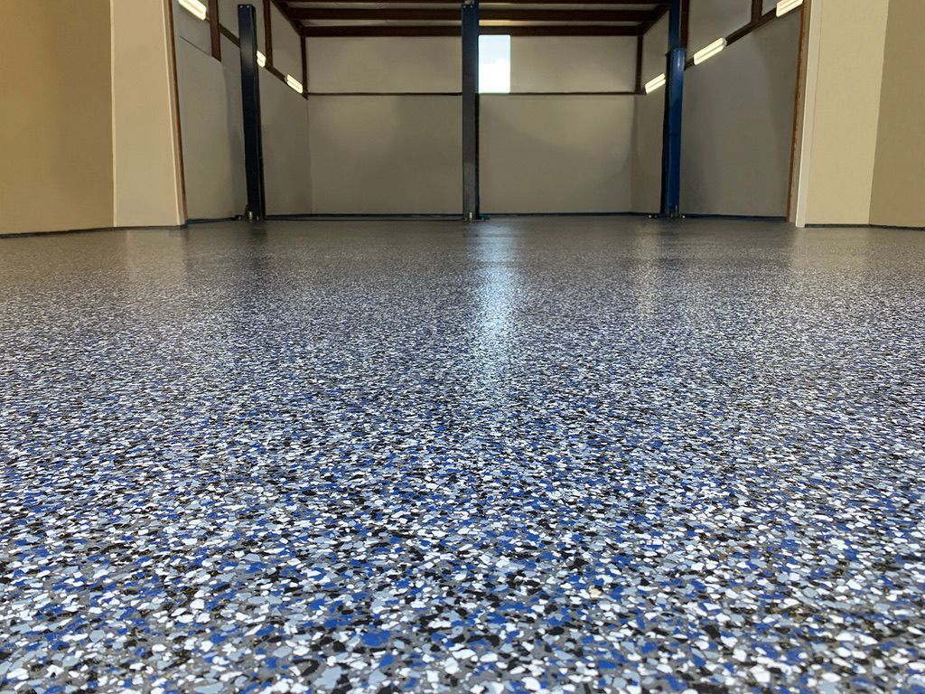 A close up of a garage floor with a lot of blue and gray flakes on it.