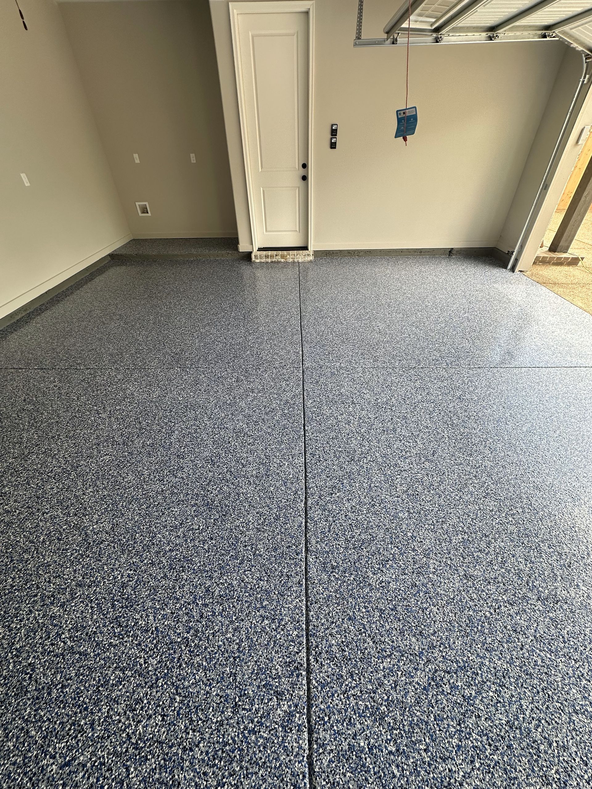 A garage with a gray floor and a white door.