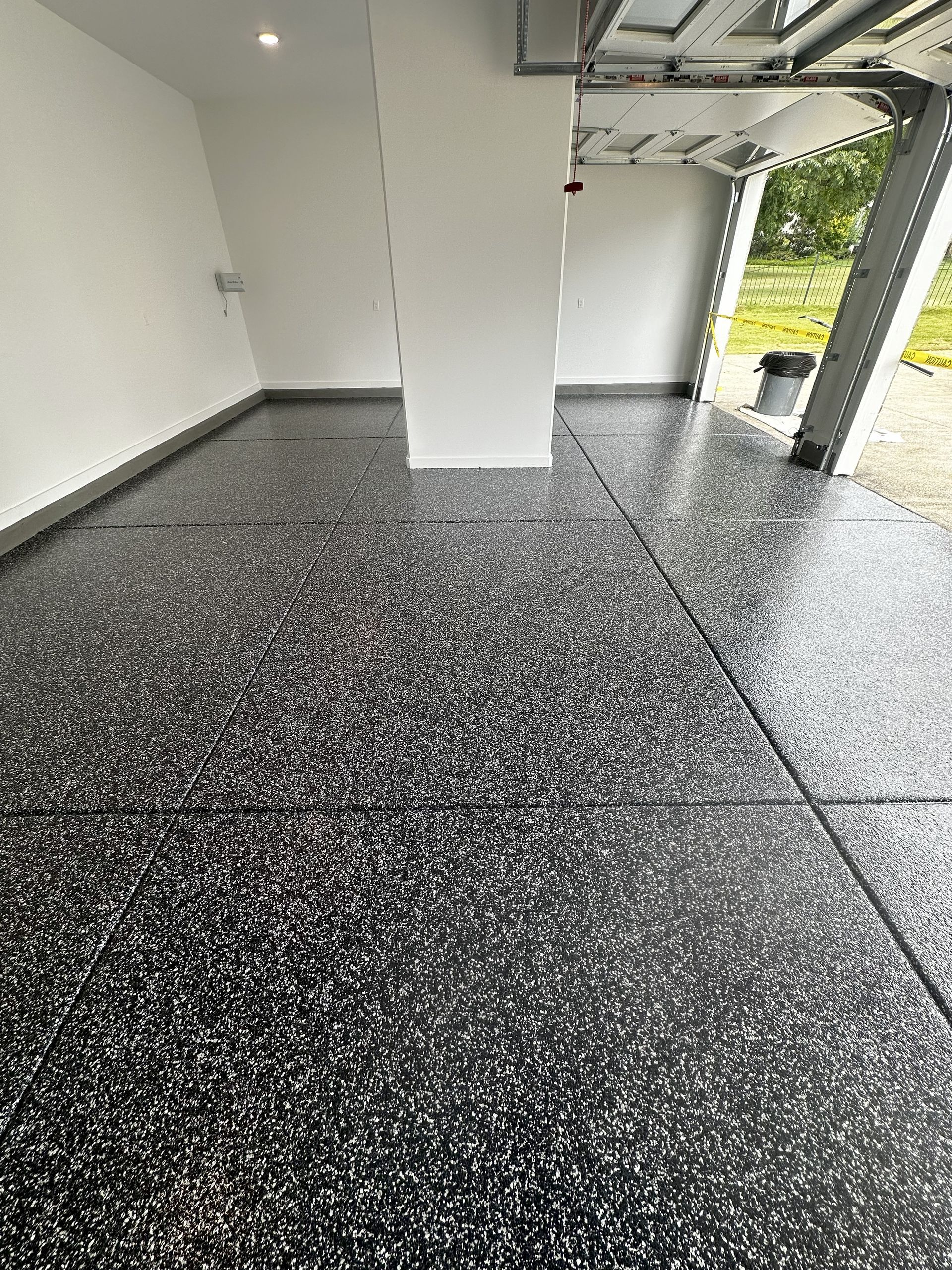 Garage with a speckled black and white epoxy floor.
