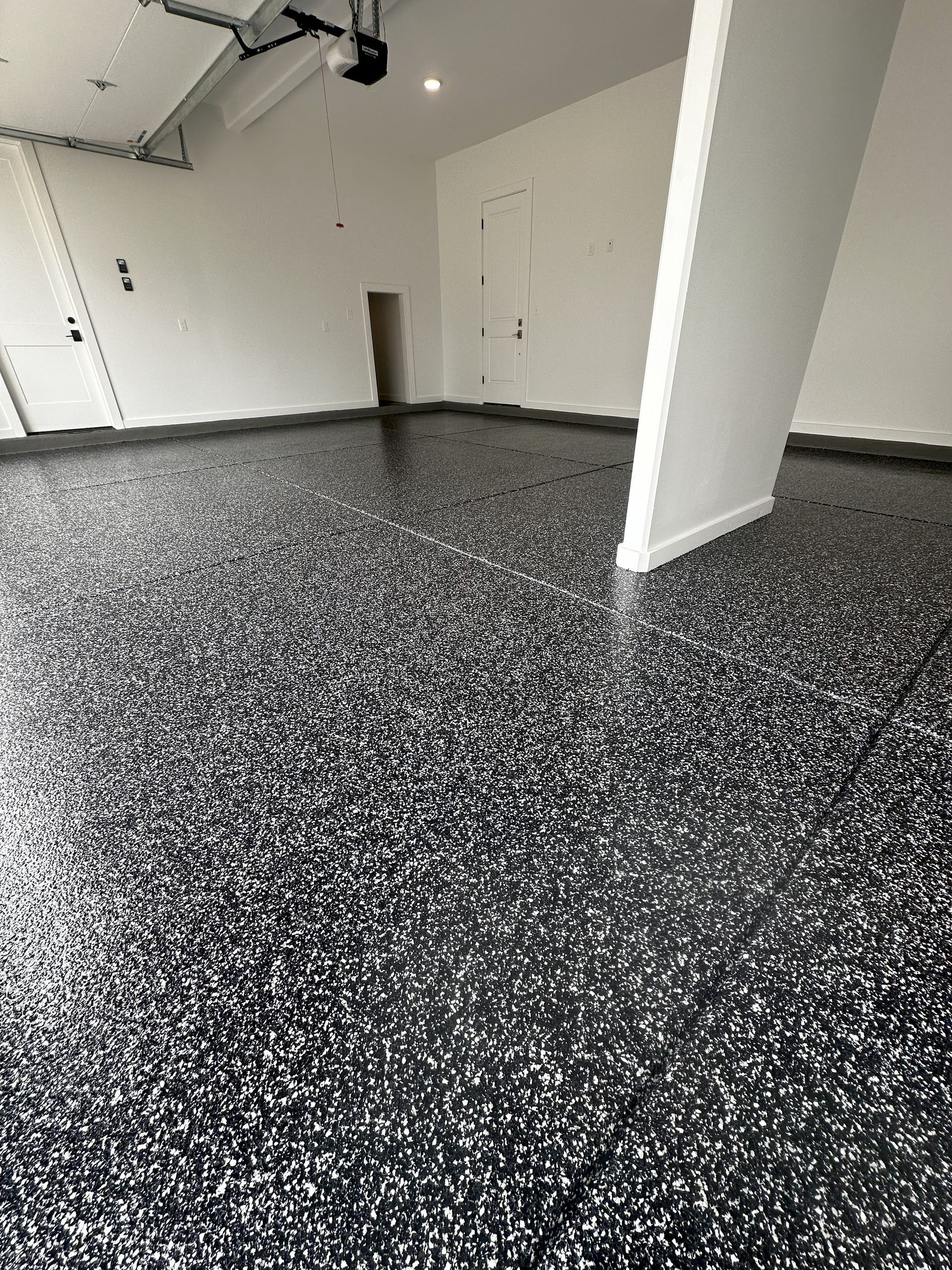 Garage with black and white speckled epoxy floor.
