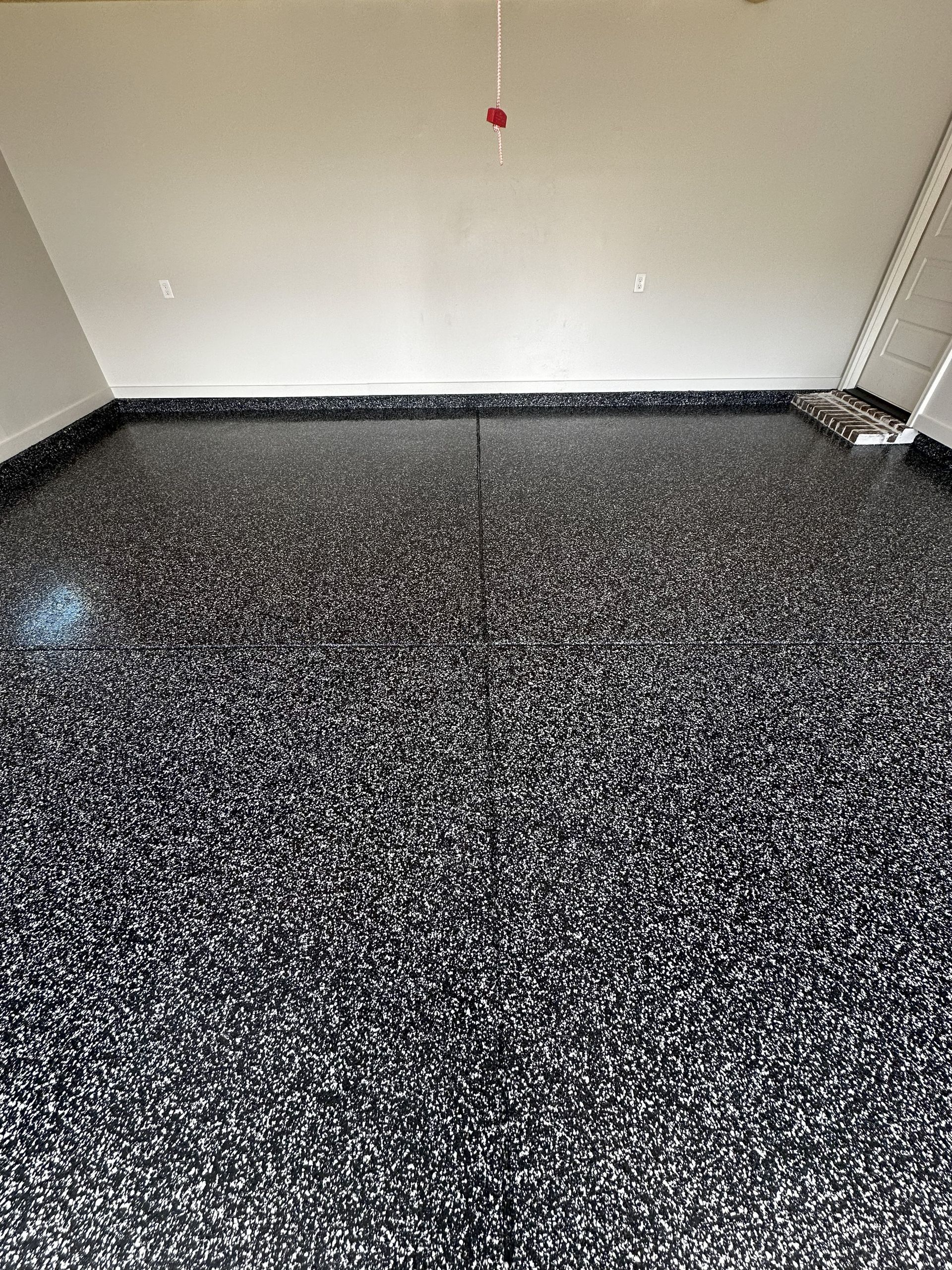 Garage floor coated in black epoxy with white and gray flakes.