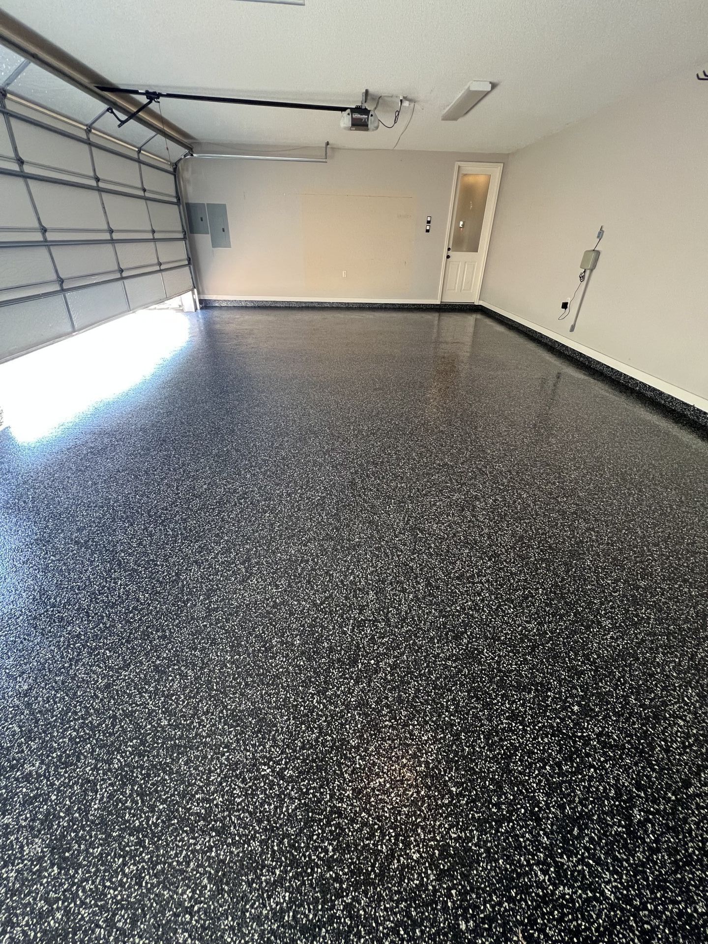 A garage with a black and white floor and a garage door.