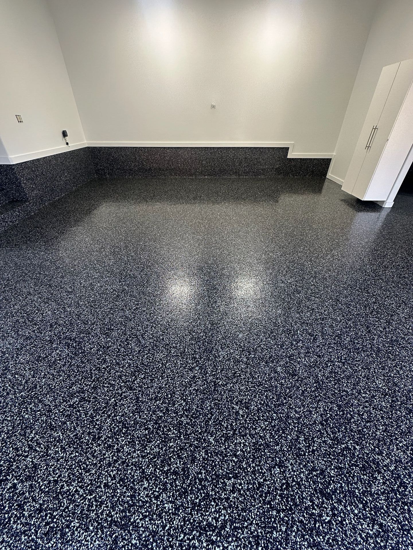 A garage with a black and white floor and white walls.