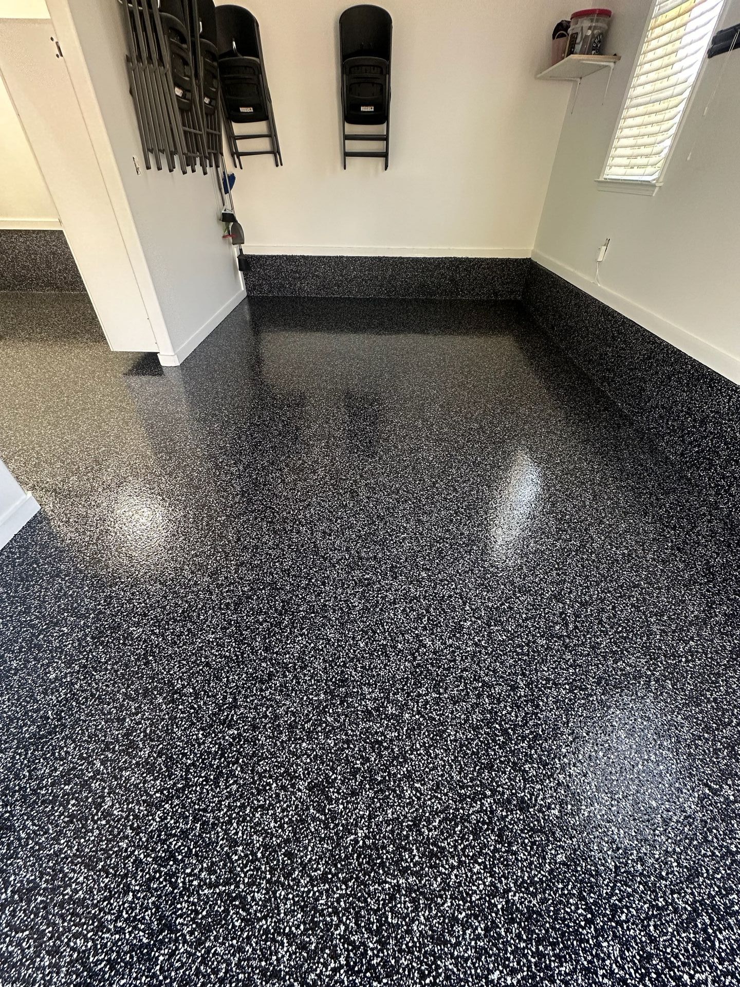 A garage with a black and white floor and chairs on the wall.