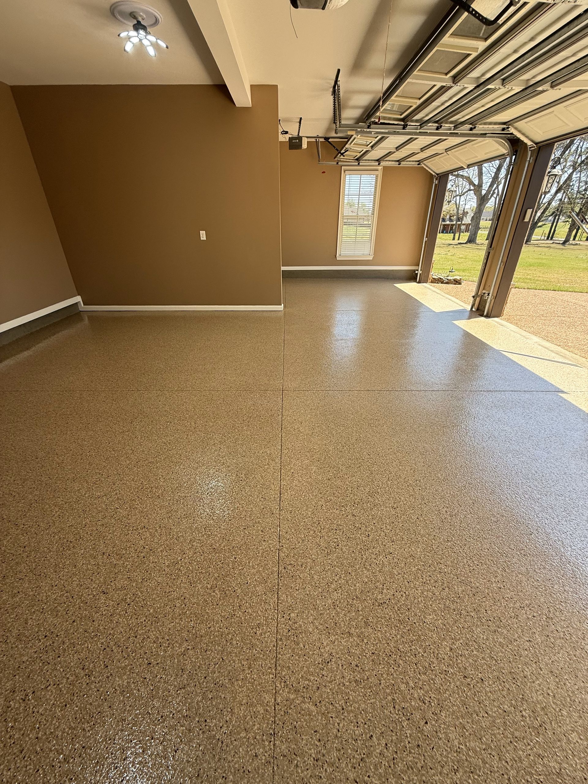 An empty garage with a garage door open and a ceiling fan.