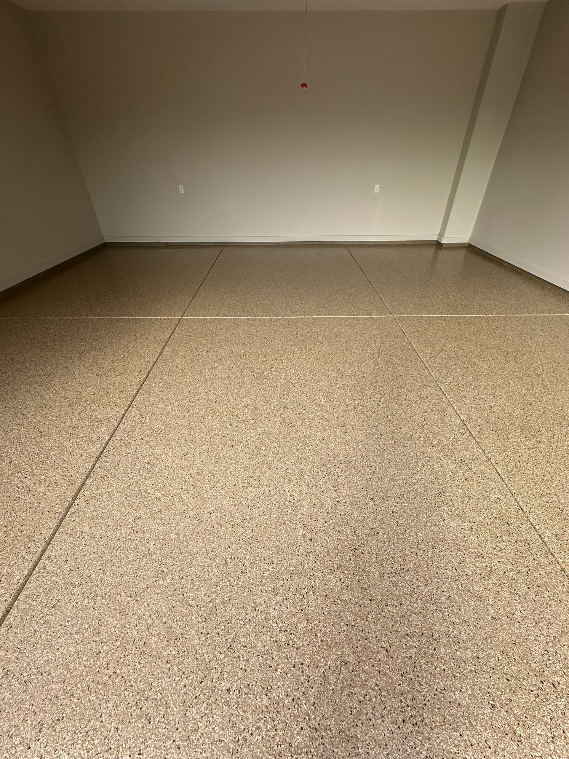 A large empty room with a brown floor and white walls.