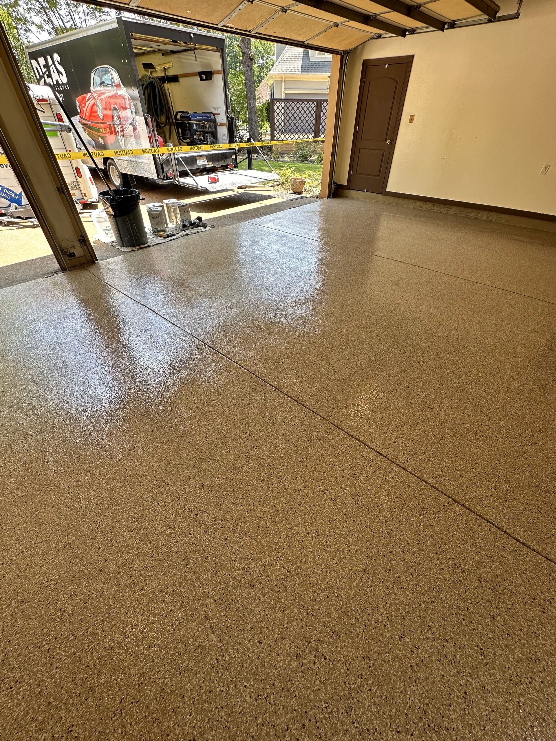 A garage with a shiny floor and a truck parked in the background.