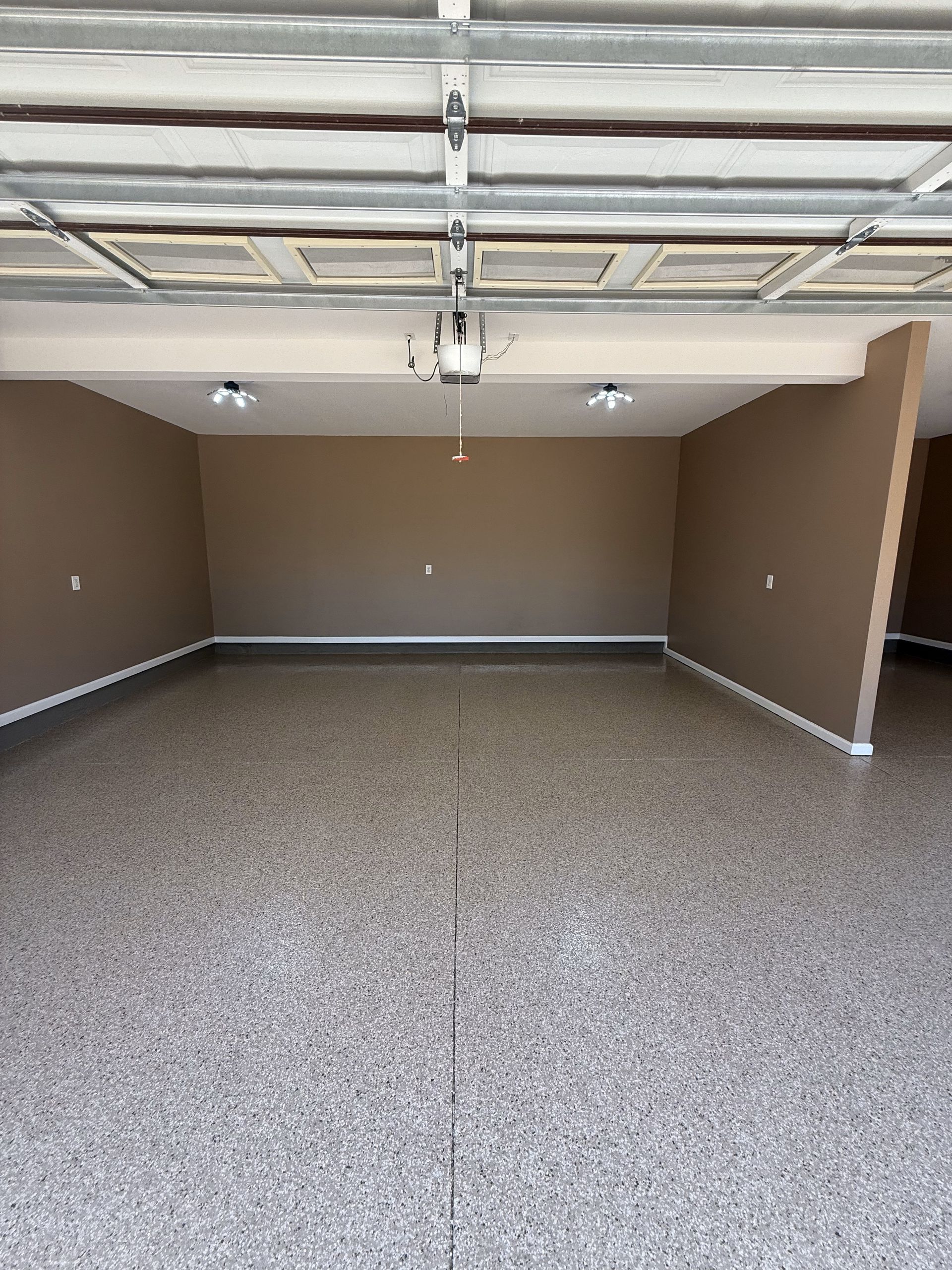An empty garage with a garage door open and a concrete floor.