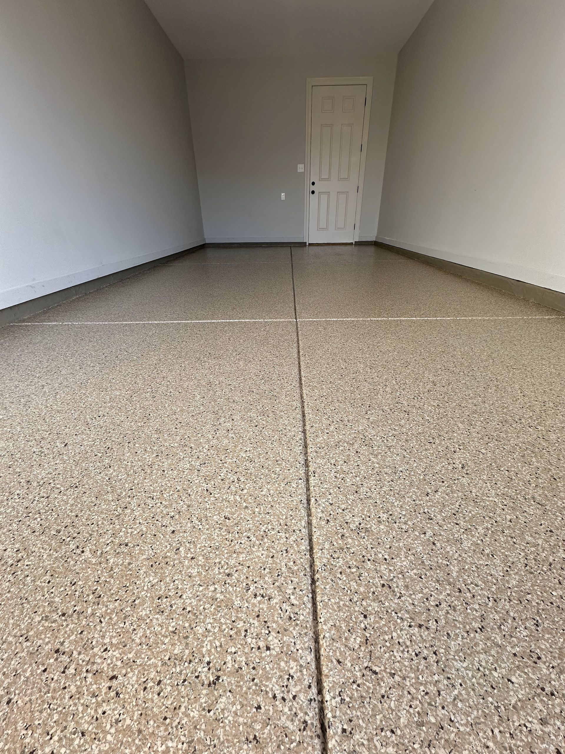 A large empty room with a concrete floor and a door.