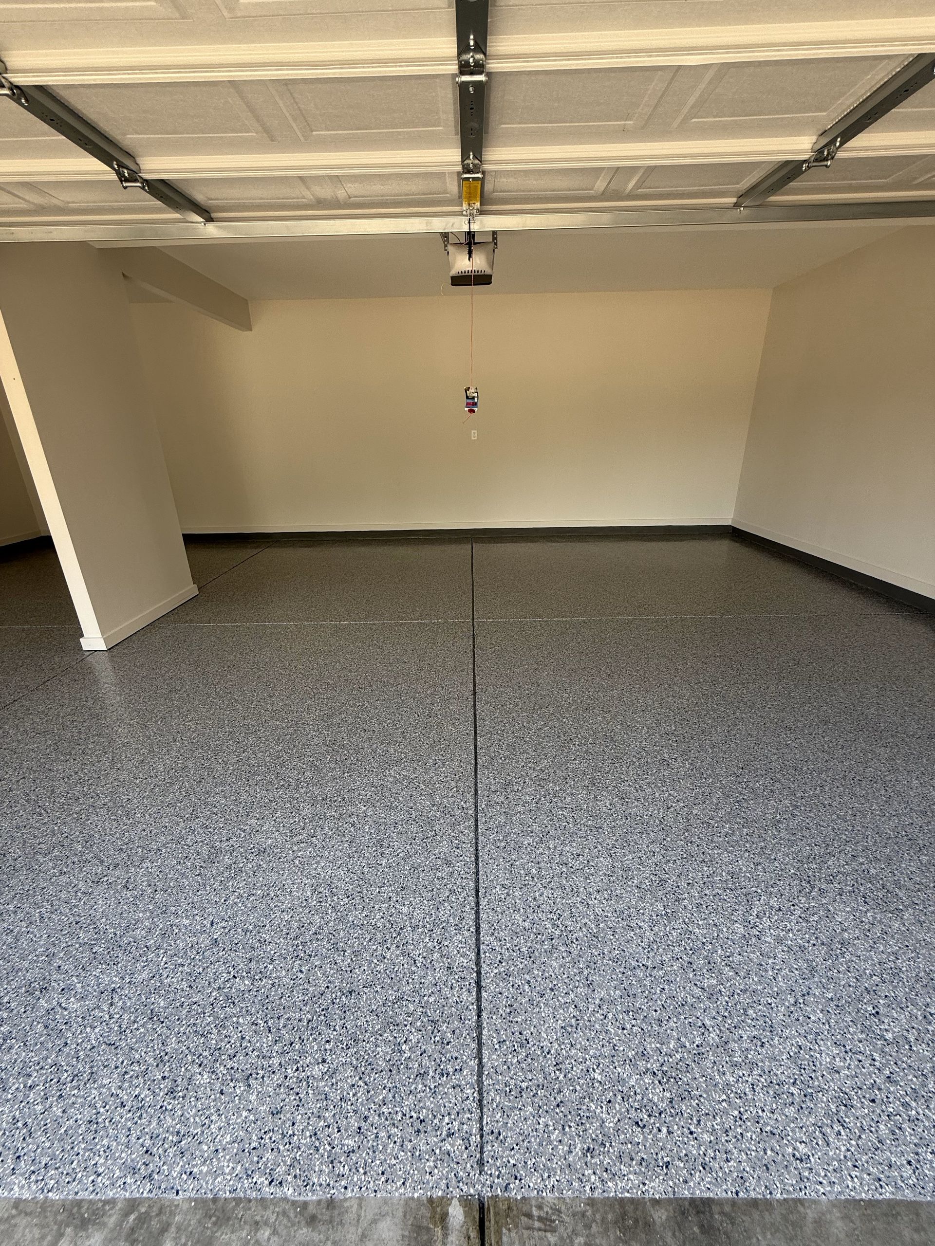 A garage with a garage door open and a gray floor.