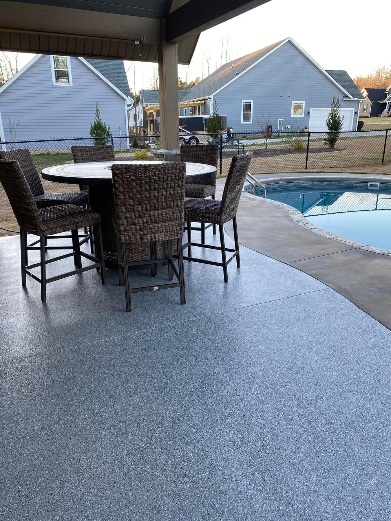 A patio with a table and chairs next to a pool.