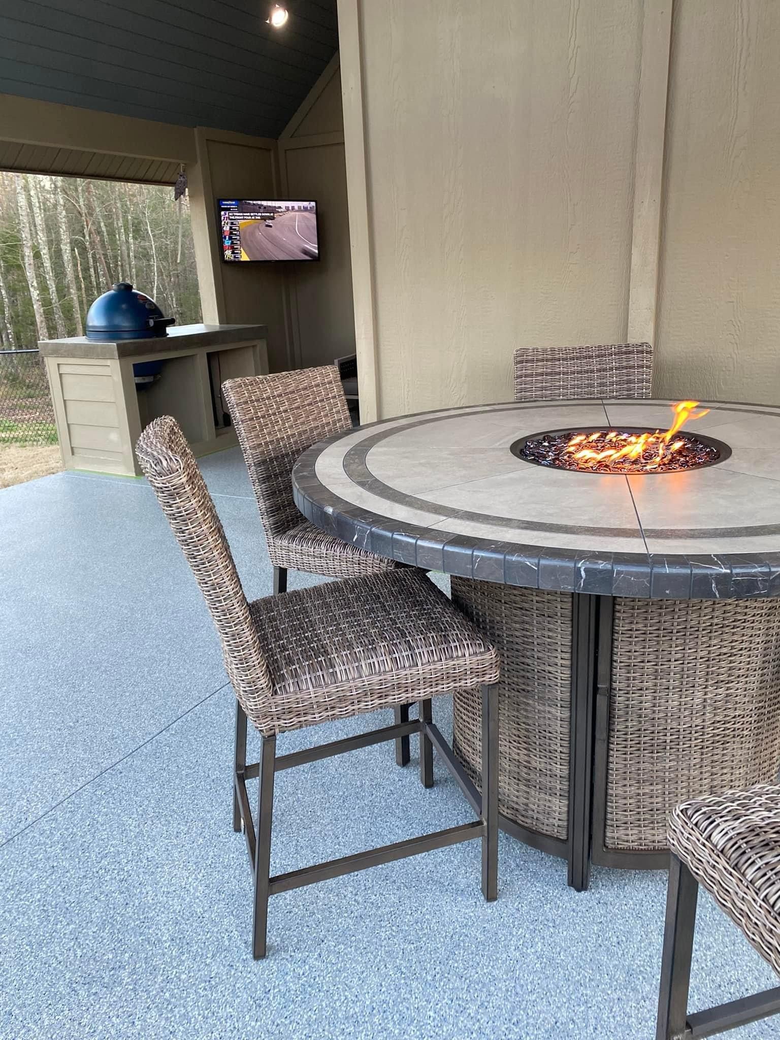 A patio with a table and chairs and a fire pit.